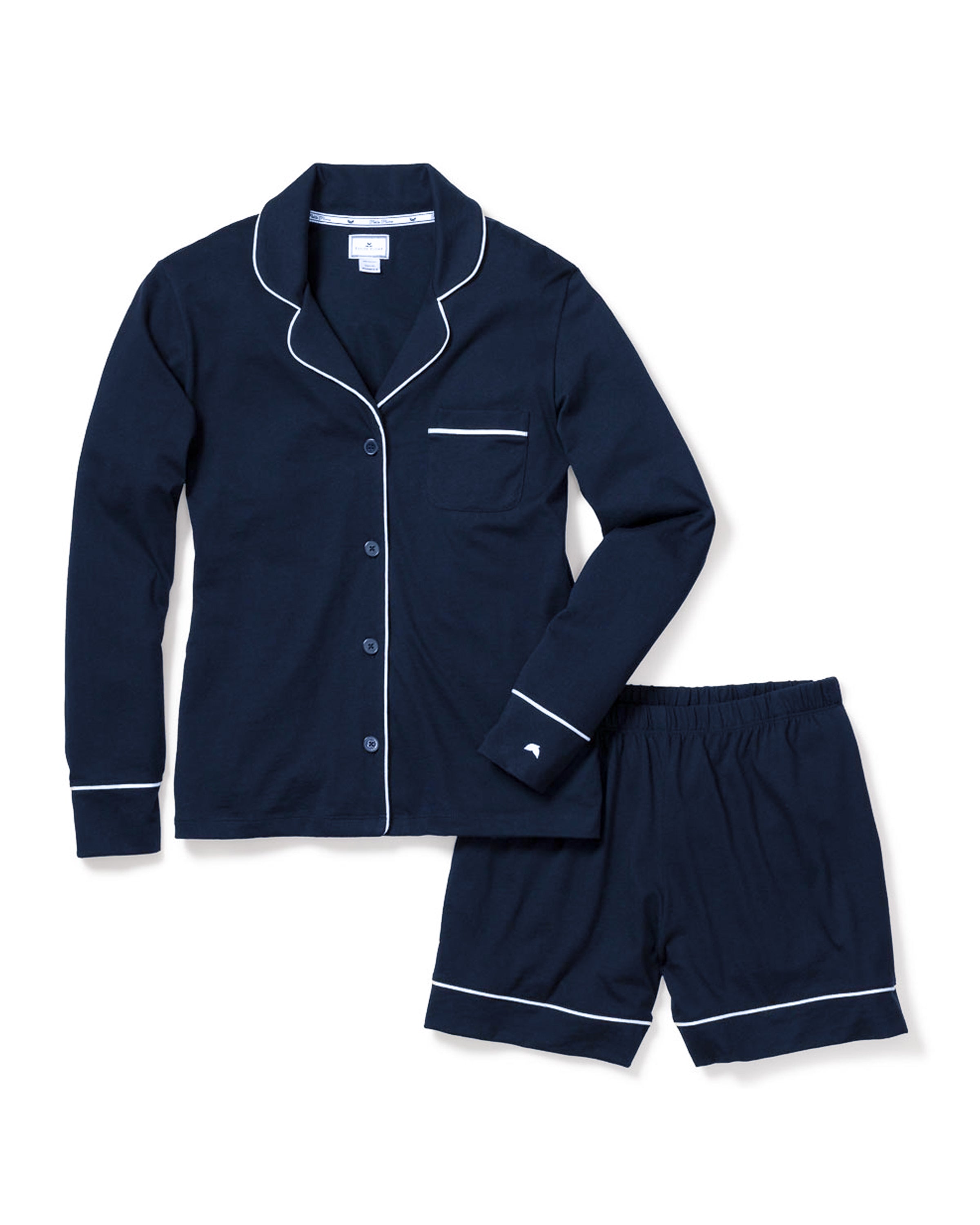 The Womens Pima Long Sleeve Short Set in Navy by Petite Plume is a classic pajama ensemble crafted from luxurious Peruvian Pima cotton. It features a long-sleeve button-up top with white piping and a pocket, paired with matching shorts for ultimate comfort and style.