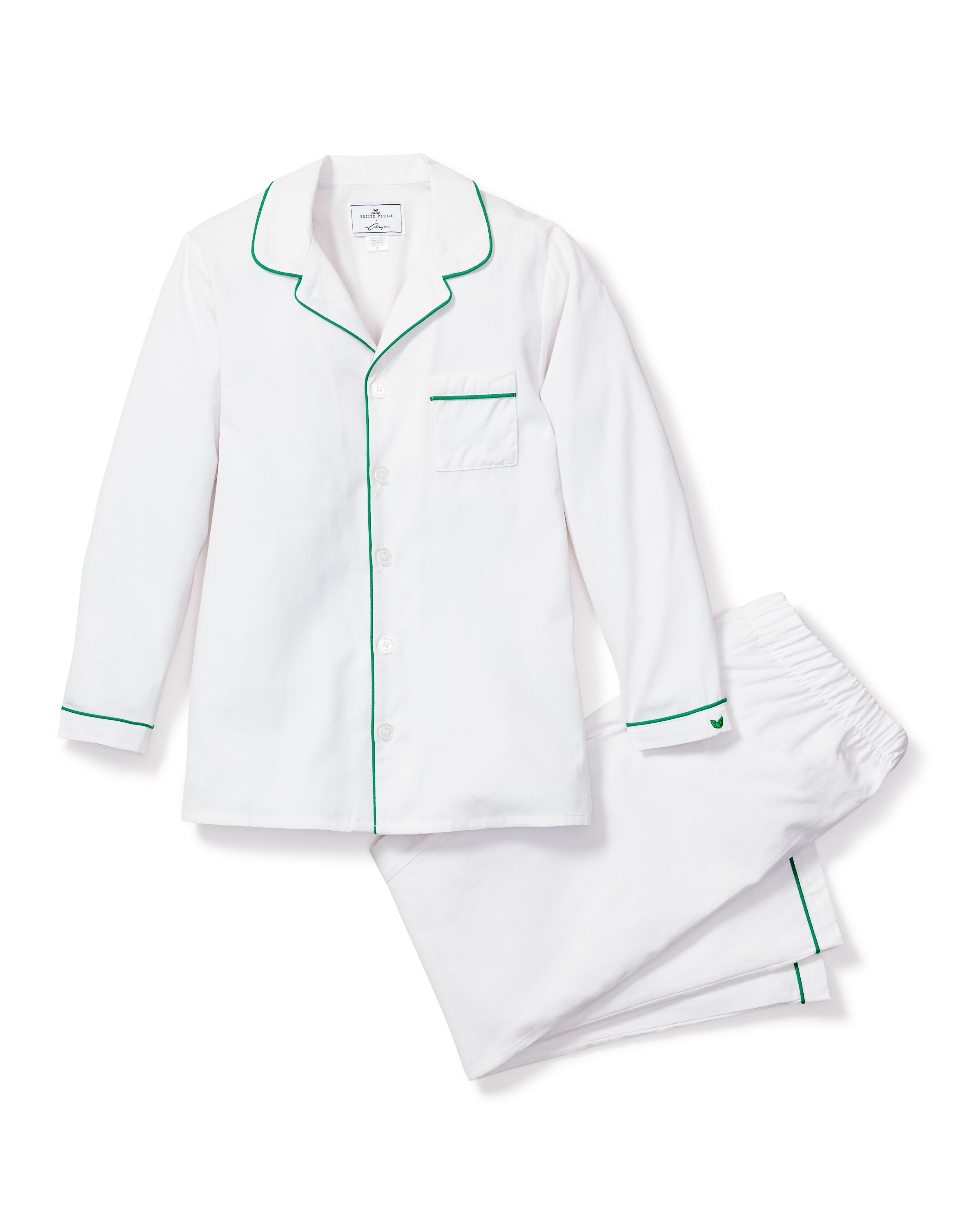 The Kids Twill Pajama Set by Petite Plume features a button-up long-sleeve shirt and pants in classic white, accented with green piping on the cuffs, collar, and pocket. Designed for comfort, it includes a left chest pocket. This flame-retardant sleepwear ensures peace of mind.