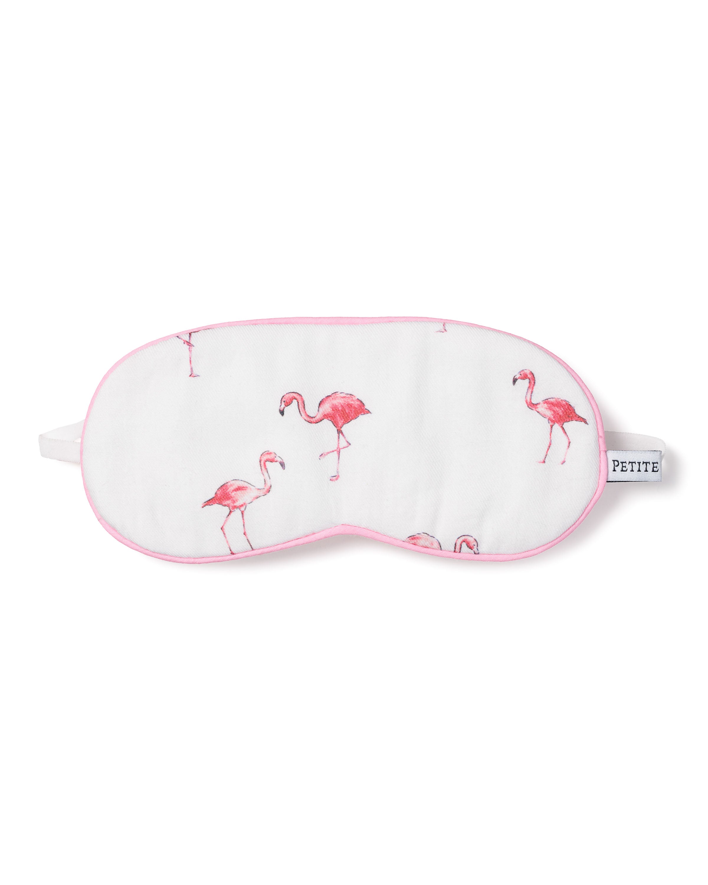 The Kids Sleep Mask in Flamingos by Petite Plume features a white fabric with pink flamingo illustrations and an elegant pink trim. The PETITE tag completes this tropical chic accessory, perfect for dreamy nights with matching eye masks.