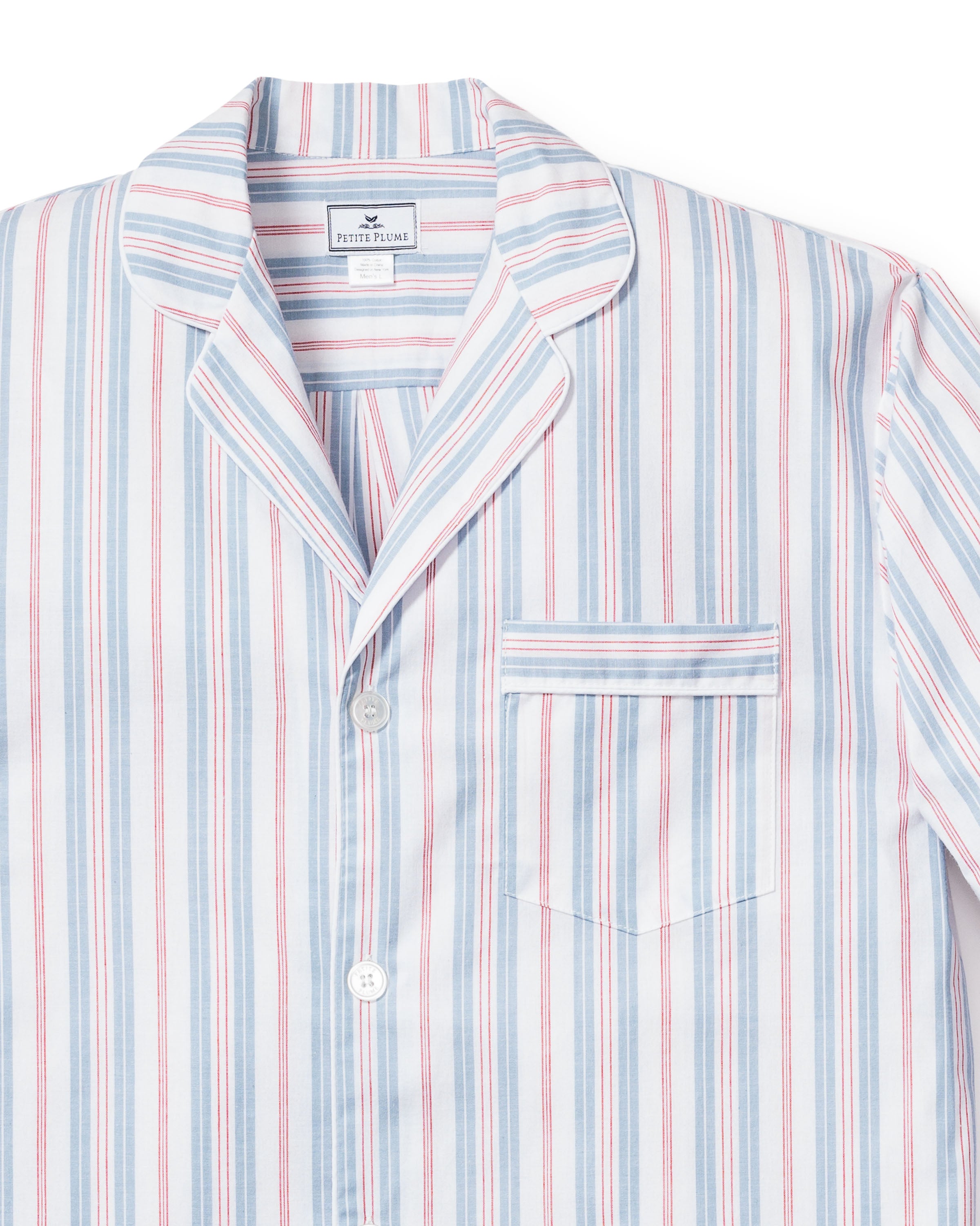 A detailed view of the Petite Plume Mens Twill Pajama Short Set in Vintage French Stripes, featuring blue, red, and white lines. Made from 100% cotton with a notched collar, button front, and chest pocket. An inner label highlights its premium quality.
