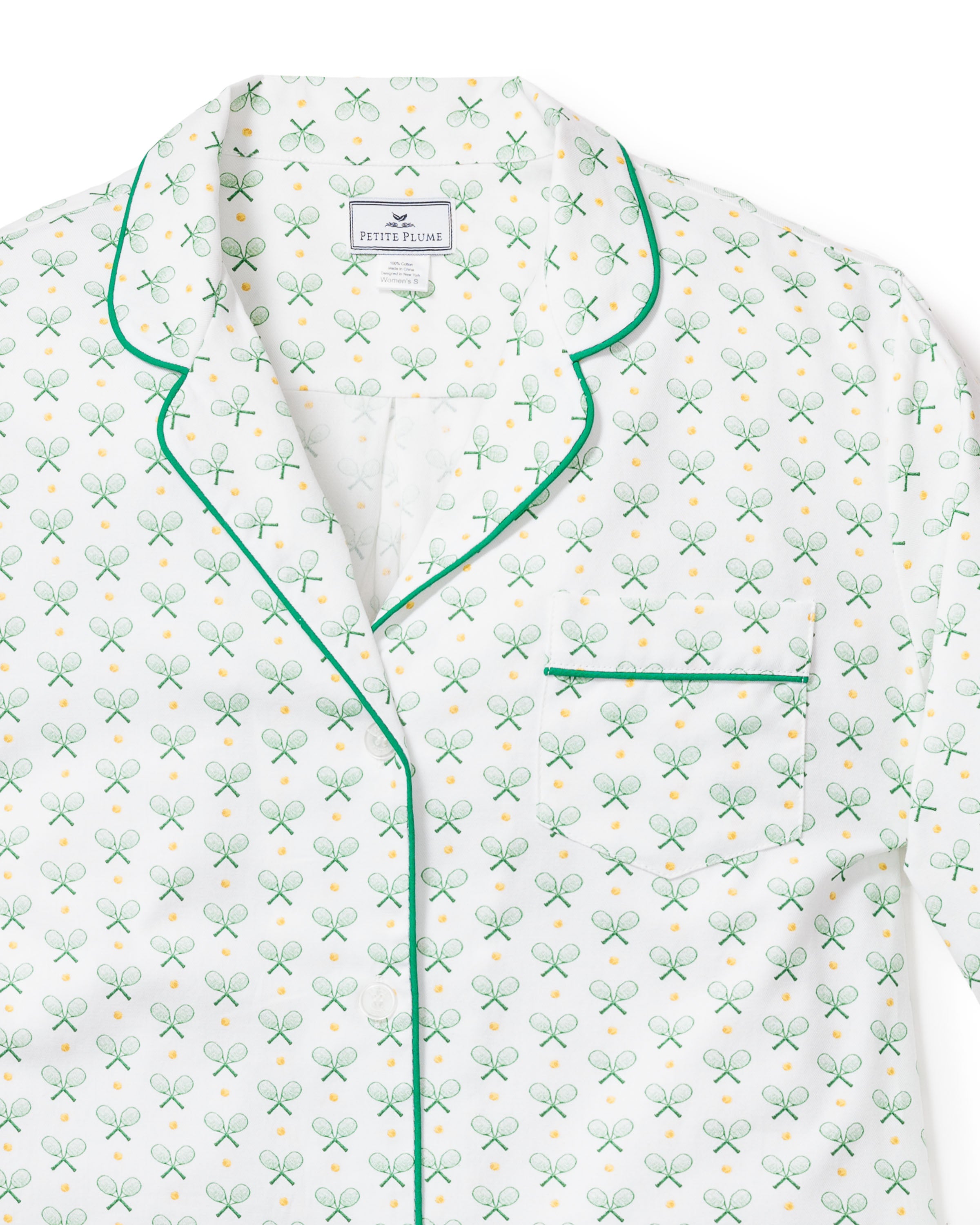 Close-up of the Womens Twill Pajama Short Sleeve Short Set in Match Point by Petite Plume, featuring a green and gold tennis racket and ball pattern. These luxury pajamas have dark green piping on the collar, pocket, and buttons, with Petite Plume labeled inside for style and comfort.