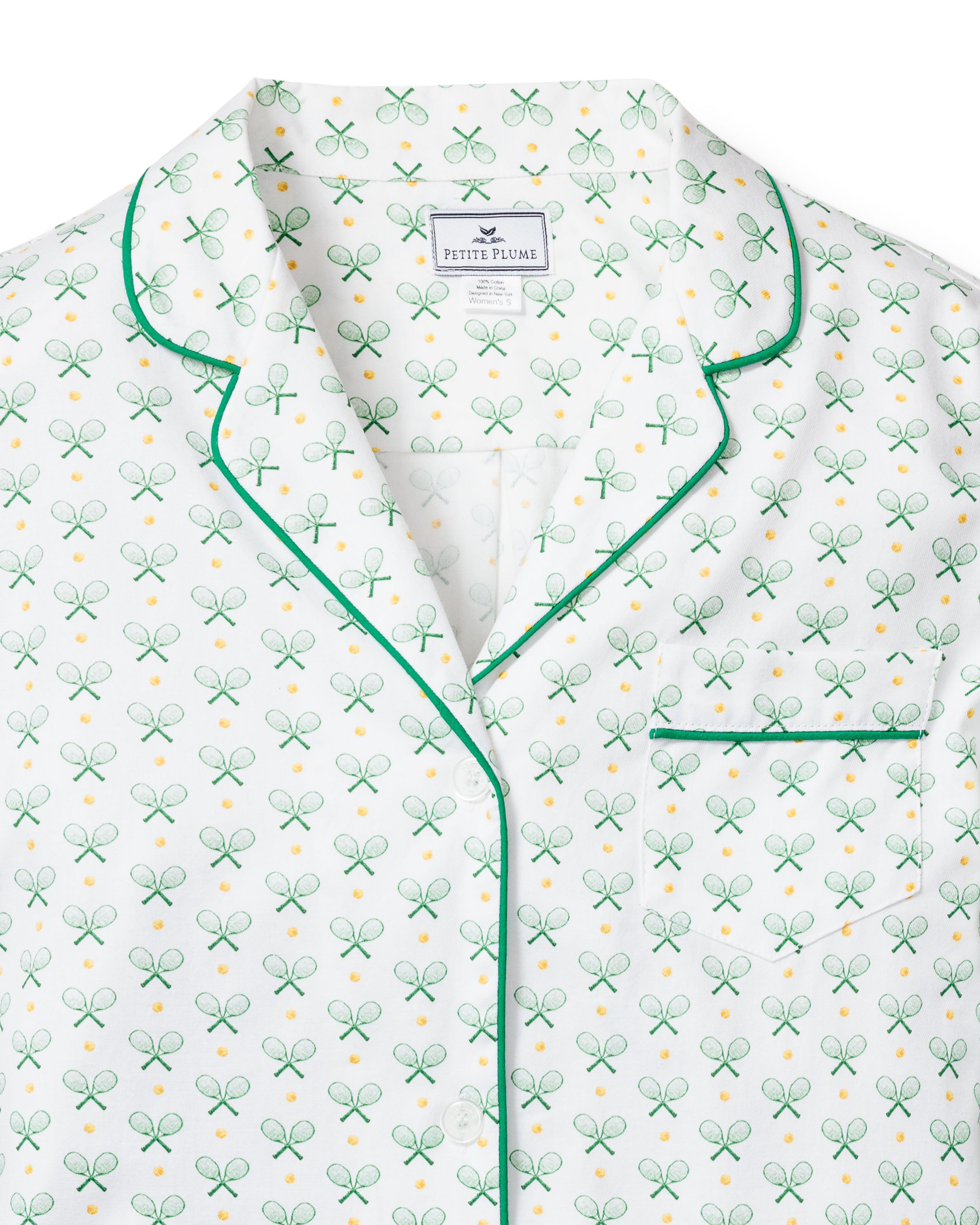 The Womens Twill Nightshirt in Match Point by Petite Plume is luxury sleepwear, showcasing a playful tennis print with green rackets and yellow balls. It features green piping on the collar and includes a single chest pocket, with the Petite Plume label inside.