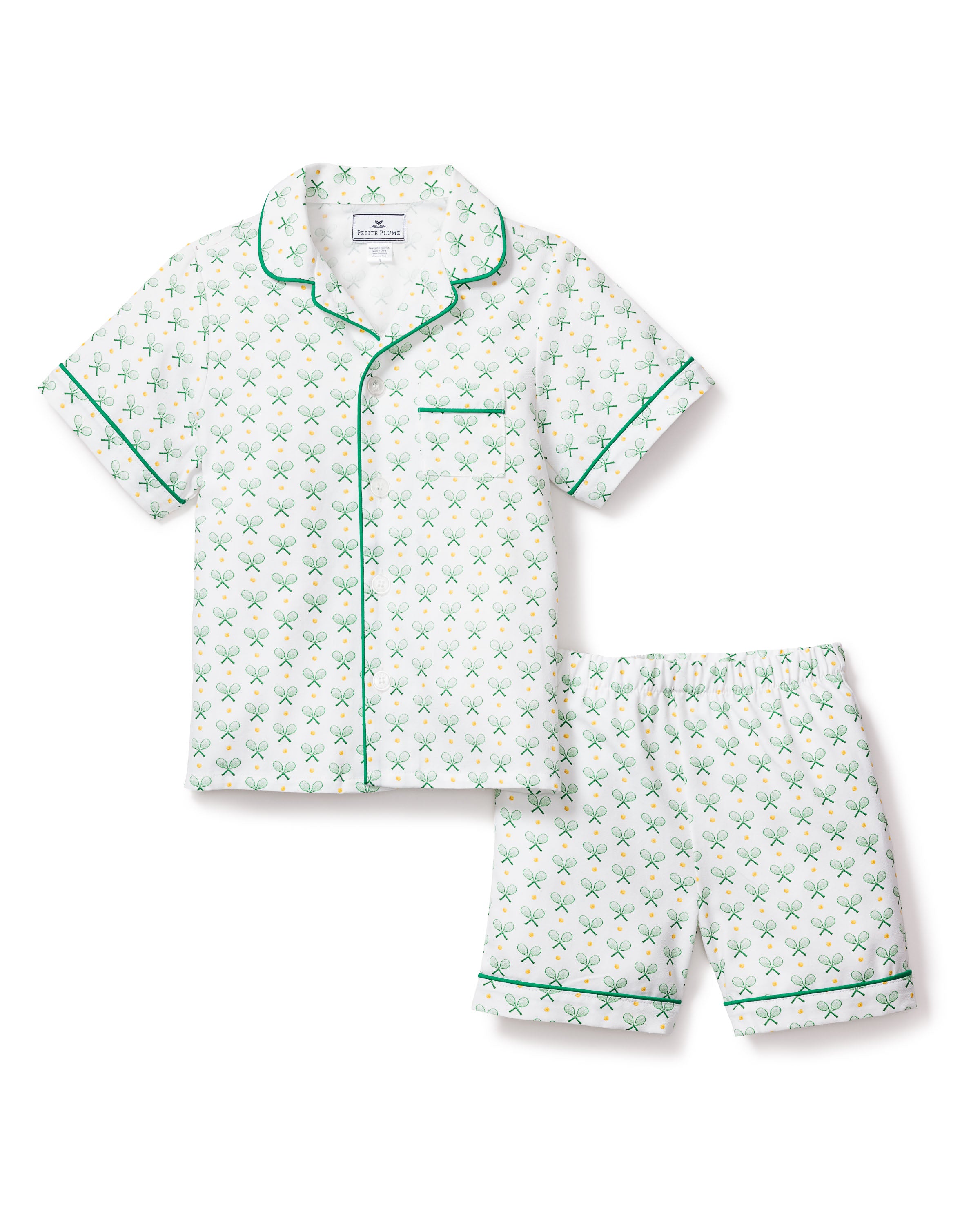 The Kids Twill Pajama Short Set in Match Point by Petite Plume features a classic short-sleeve, button-up style with a collar, adorned with green tennis rackets on white. It includes elegant green piping for a refined look.
