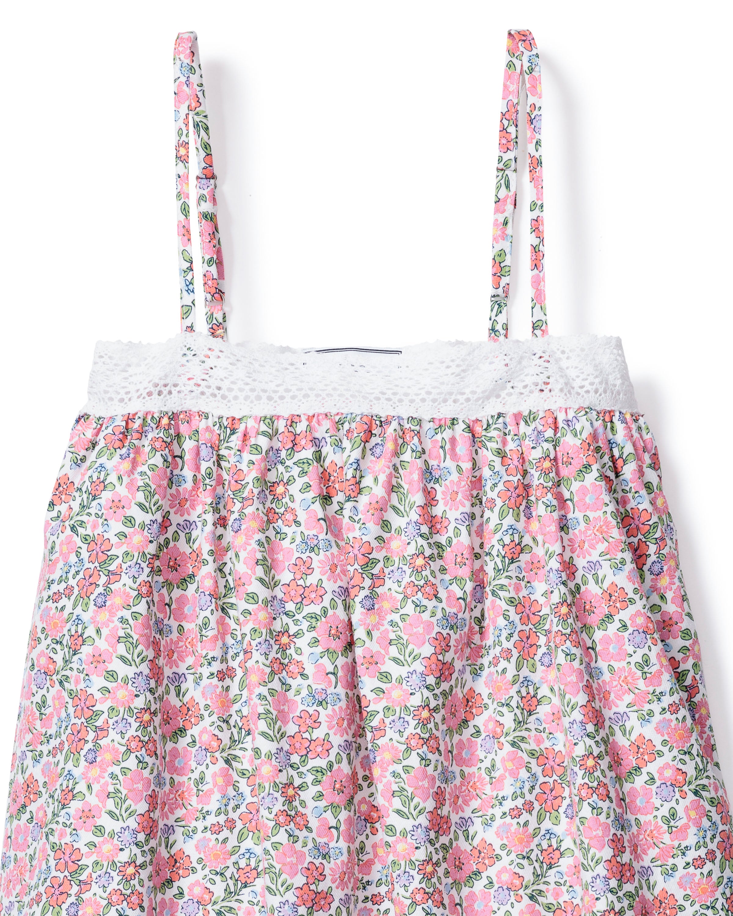 The Girls Twill Lily Nightgown in Fleurs de Rose by Petite Plume is a floral sundress with thin straps and lace-trimmed neckline. It features pink, red, and blue flowers with green leaves on a white background, offering a light and summery vibe.