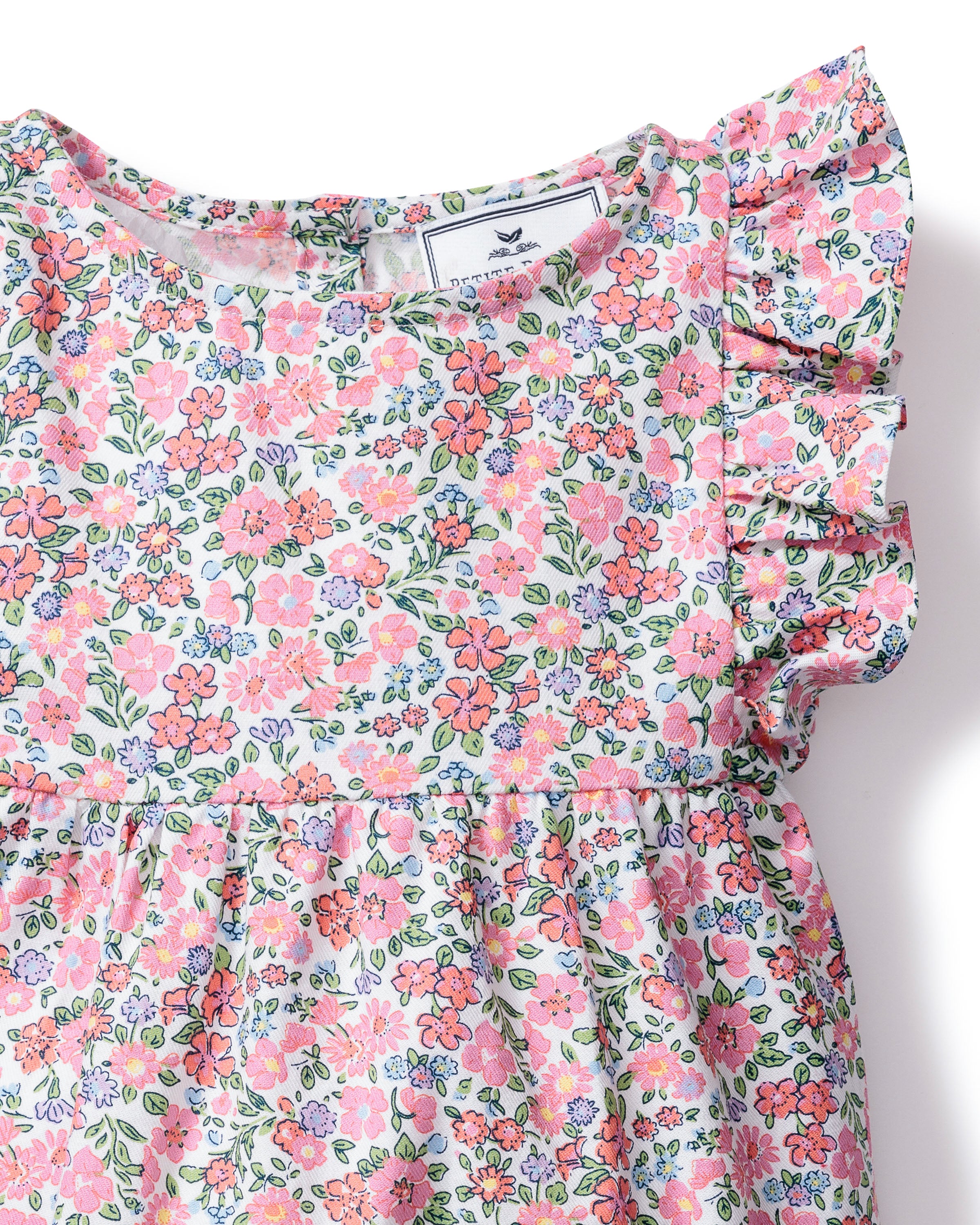 A detailed view of the Babys Twill Ruffled Romper in Fleurs de Rose by Petite Plume showcases pink and orange flowers with green leaves on white. Made from premium cotton, this romper features ruffled short sleeves and a gathered waist for elegance.