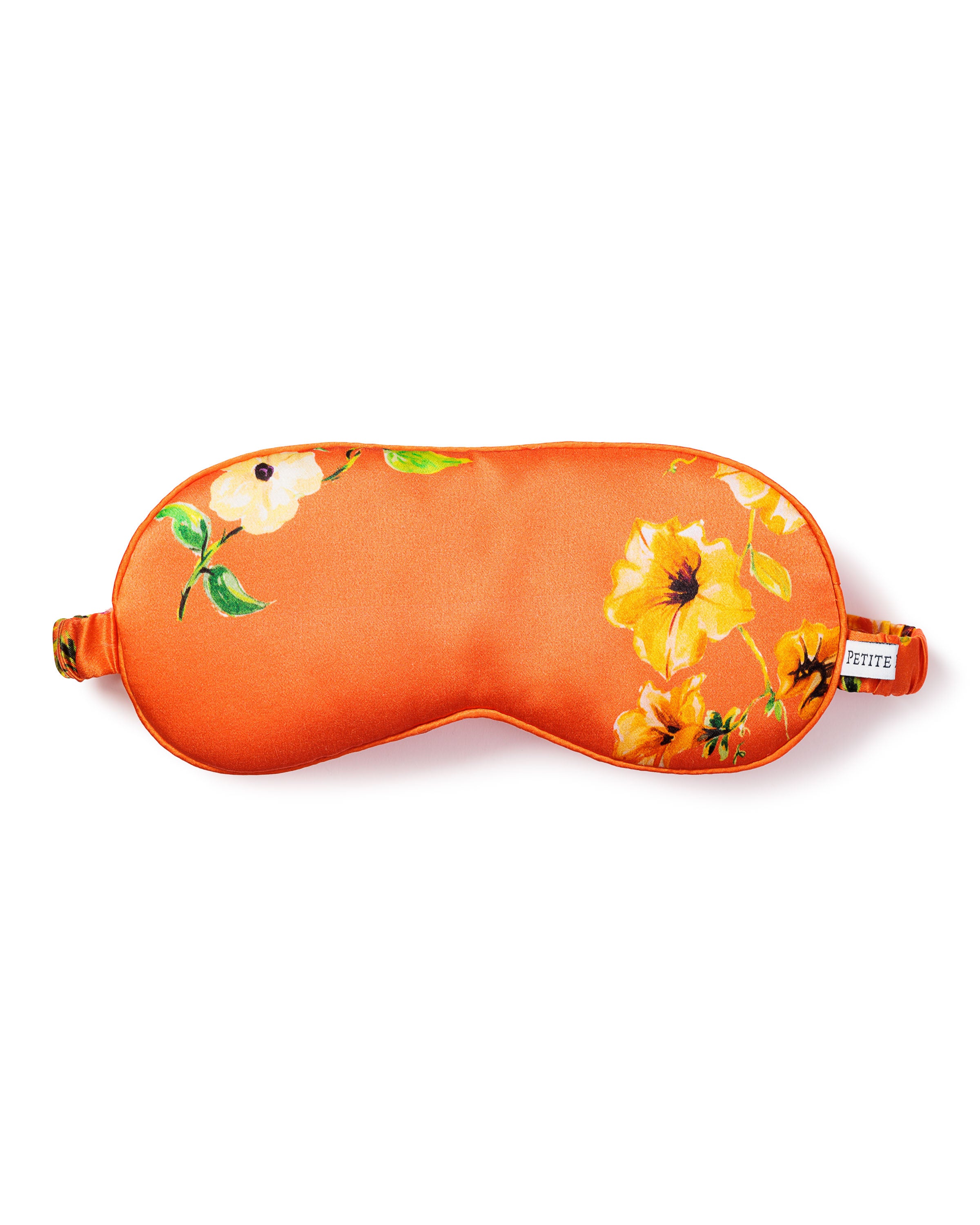 The Womens Silk Sleep Mask in Tangerine Brilliant Botanical by Petite Plume showcases yellow and white flowers on a vibrant botanical print, offering style and comfort with its smooth fabric and a small side tag.