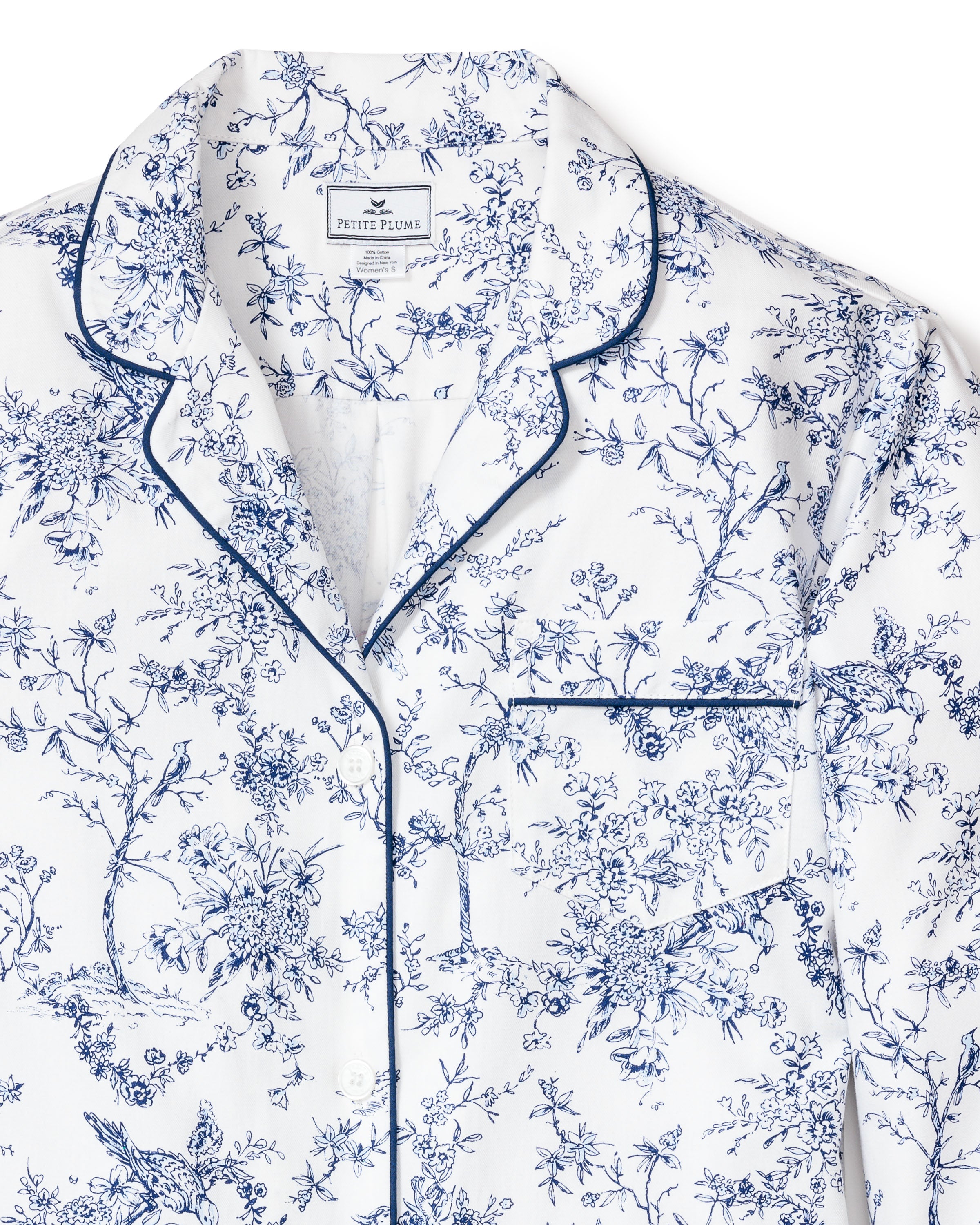The Womens Twill Nightshirt in Timeless Toile by Petite Plume exhibits botanical elegance with a blue floral print and navy piping. Made from premium cotton, it includes a chest pocket and inner collar label.