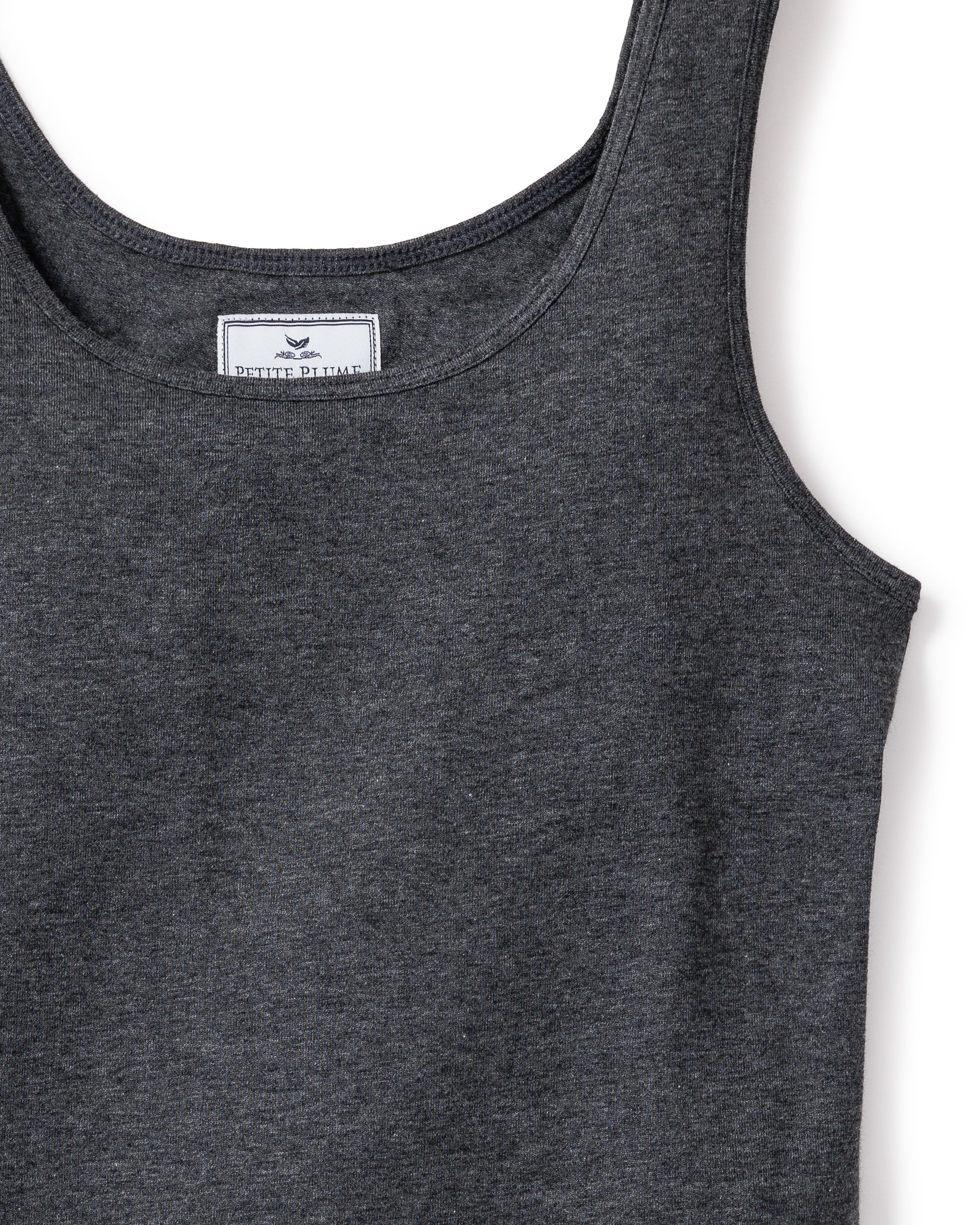 Close-up of the Womens Pima Tank Top by Petite Plume in Dark Heather Grey, showing a white label with a minimalist bird logo. Made from soft Peruvian Pima cotton, the textured fabric features smoothly finished round neckline and armholes, exuding subtle luxury.
