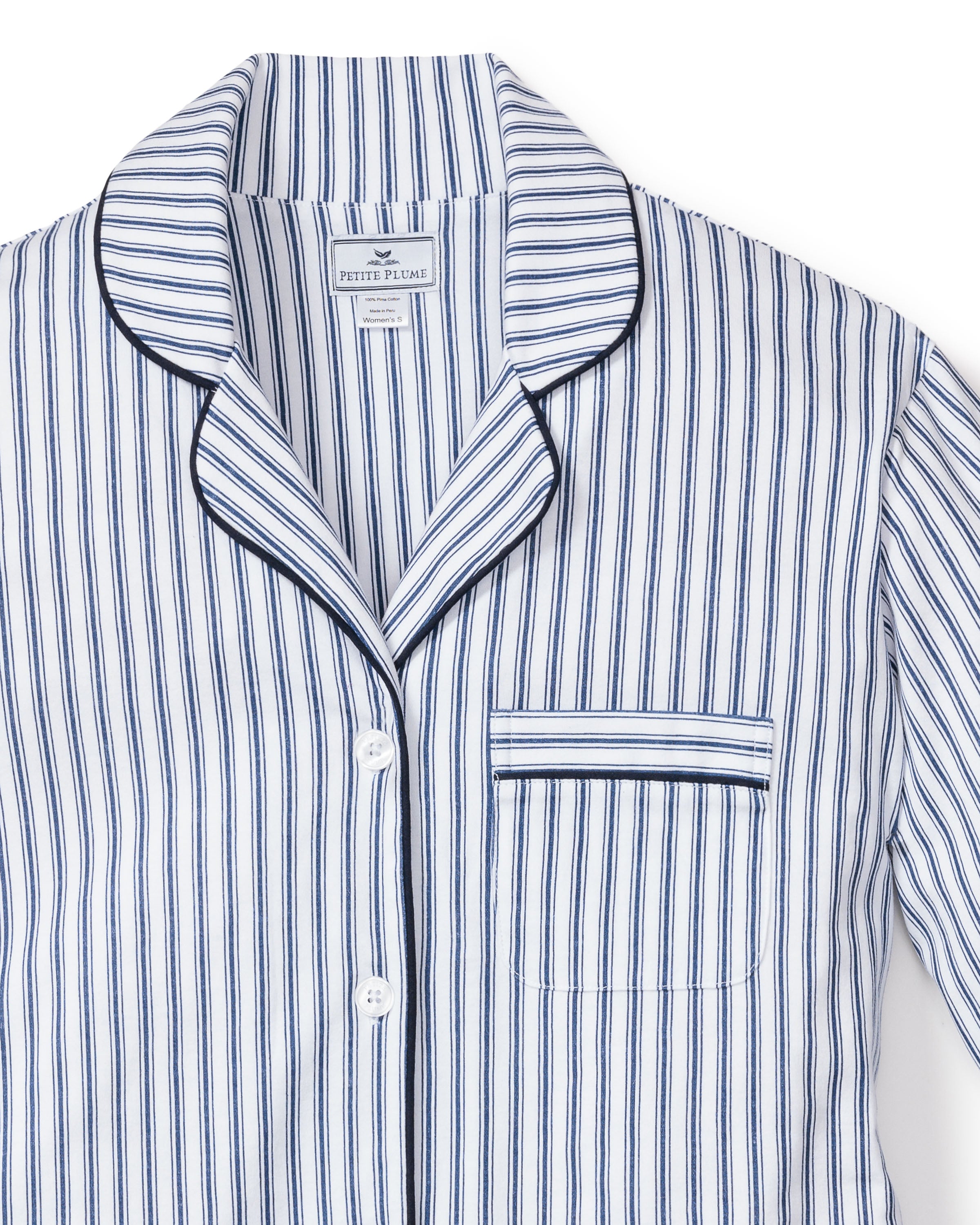 The Womens Pima Pajama Set in Navy French Ticking by Petite Plume is a luxury sleepwear piece in Pima cotton, featuring a blue and white striped top with a collar, chest pocket, white buttons, and dark piping.