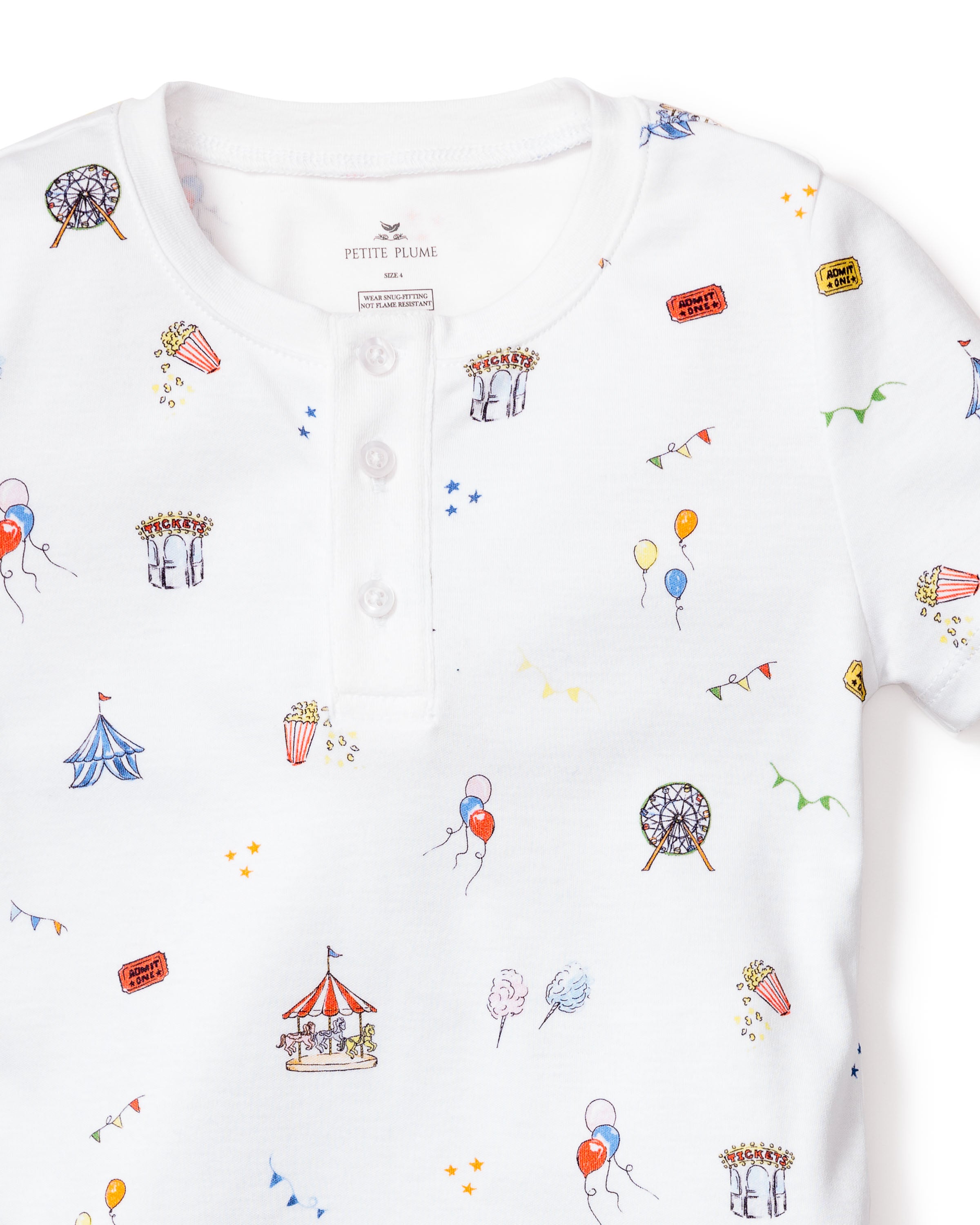 The Kids Pima Snug Fit Pajama Short Set in Carnival Memories by Petite Plume is a white shirt adorned with colorful fair-themed illustrations, including a carousel, ferris wheel, tents, balloons, cotton candy, popcorn, tickets, small stars, and has a buttoned collar. Perfect for sleepwear.