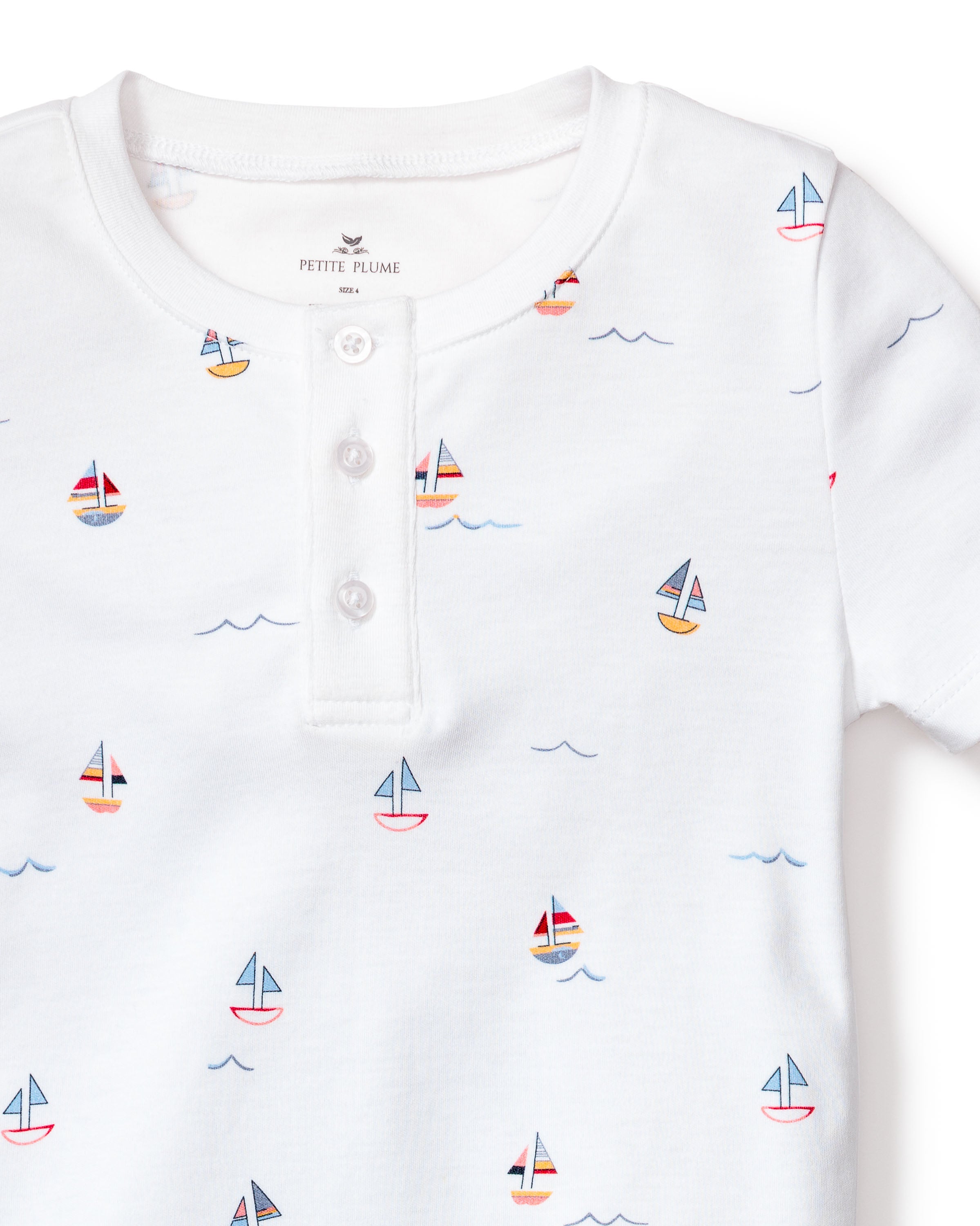 The Kids Pima Snug Fit Pajama Short Set in Bateau by Petite Plume features a soft Pima Cotton white short-sleeve shirt with a vibrant sailboat print and a stylish three-button henley collar.