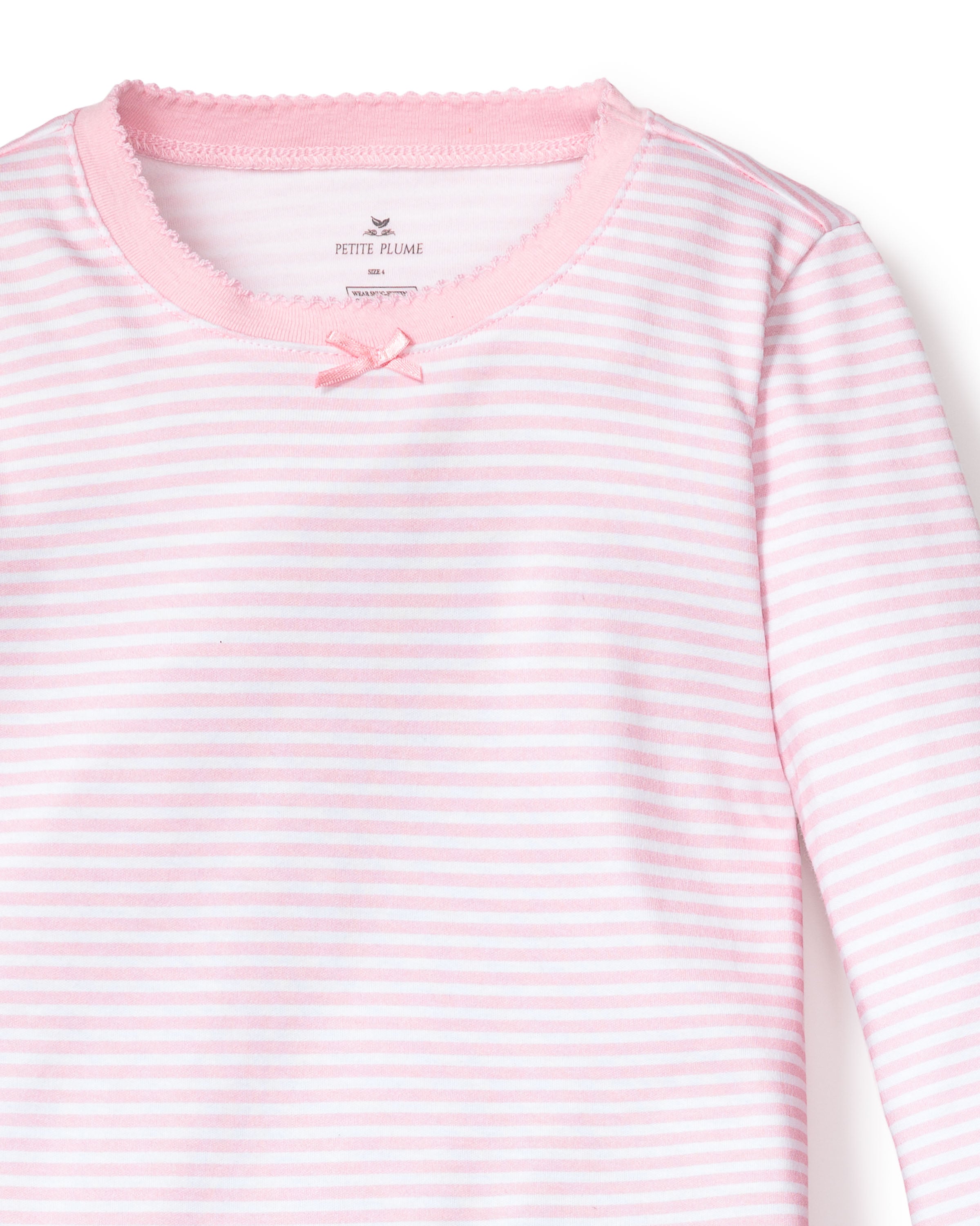 The Kids Pima Snug Fit Pajama Set in Pink Stripes by Petite Plume features a long-sleeved top made of soft Pima cotton, adorned with pink and white stripes, a round neck with pink lace trim, and a small bow for an elegant touch.
