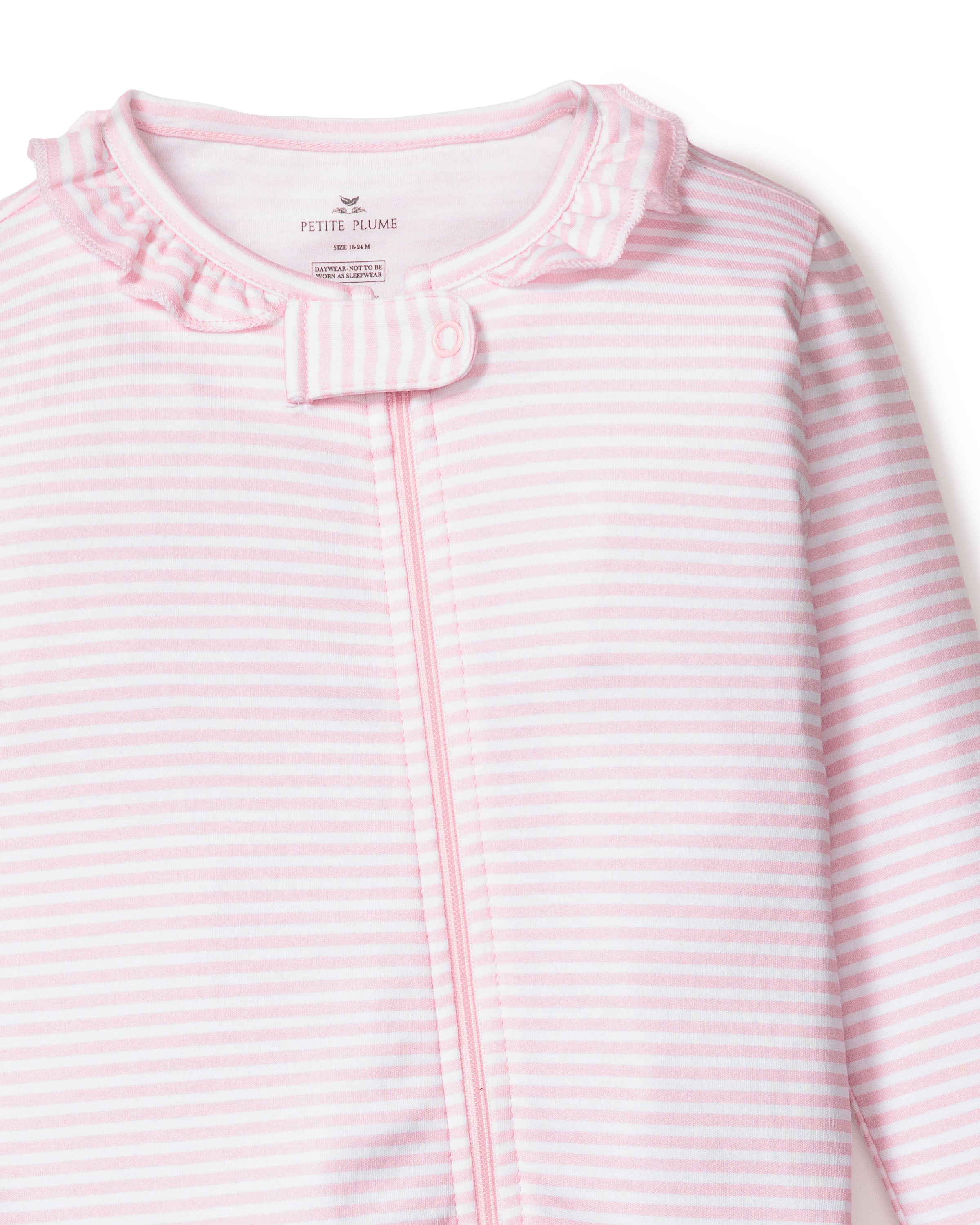 The Petite Plume Babys Pima Ruffle Collar Romper in Pink Stripes, made of soft Pima cotton, features a ruffled collar, small bow, and front zipper. The brand name is visible on the inside label.