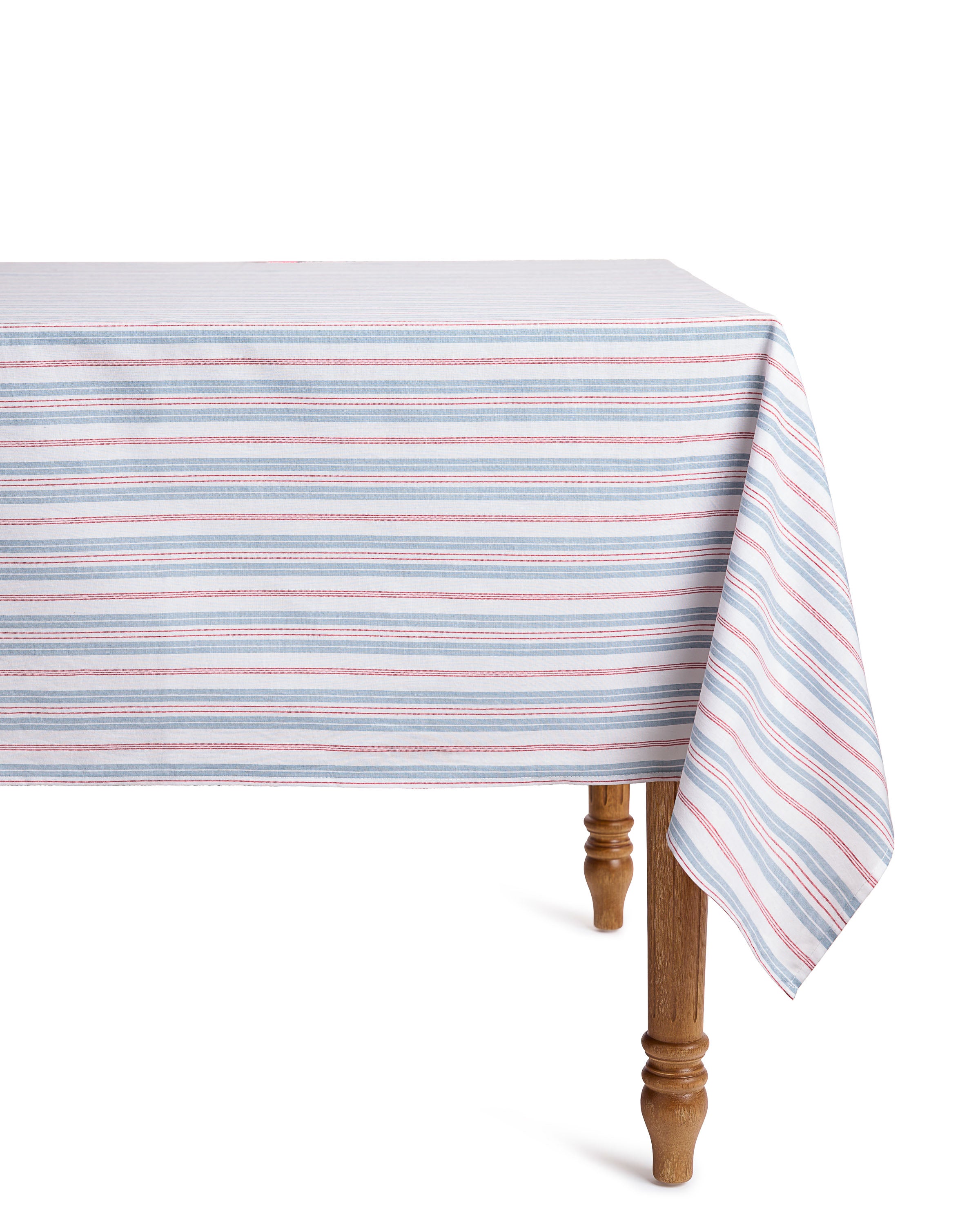The Petite Plume Signature Twill Tablecloth in Vintage French Stripes, featuring alternating light blue, pink, and white horizontal lines, drapes neatly over a wooden table. Its elegant design is ideal for a festive tablescape.#Color_Vintage French Stripes