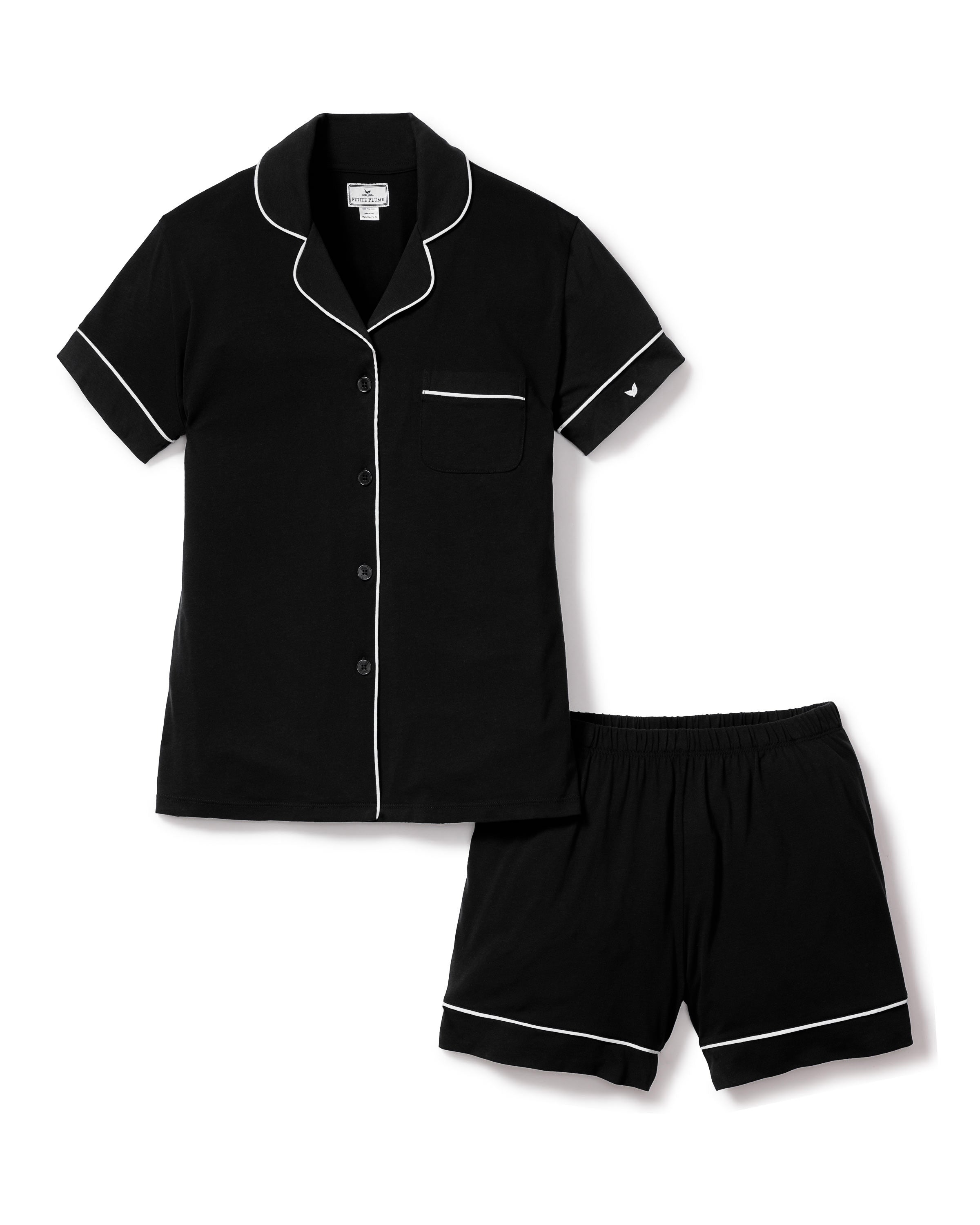 The Womens Pima Pajama Short Set in Black by Petite Plume features a luxurious jersey knit with white piping. The top has buttons and a chest pocket, while the shorts come with an elastic waistband for ultimate comfort.