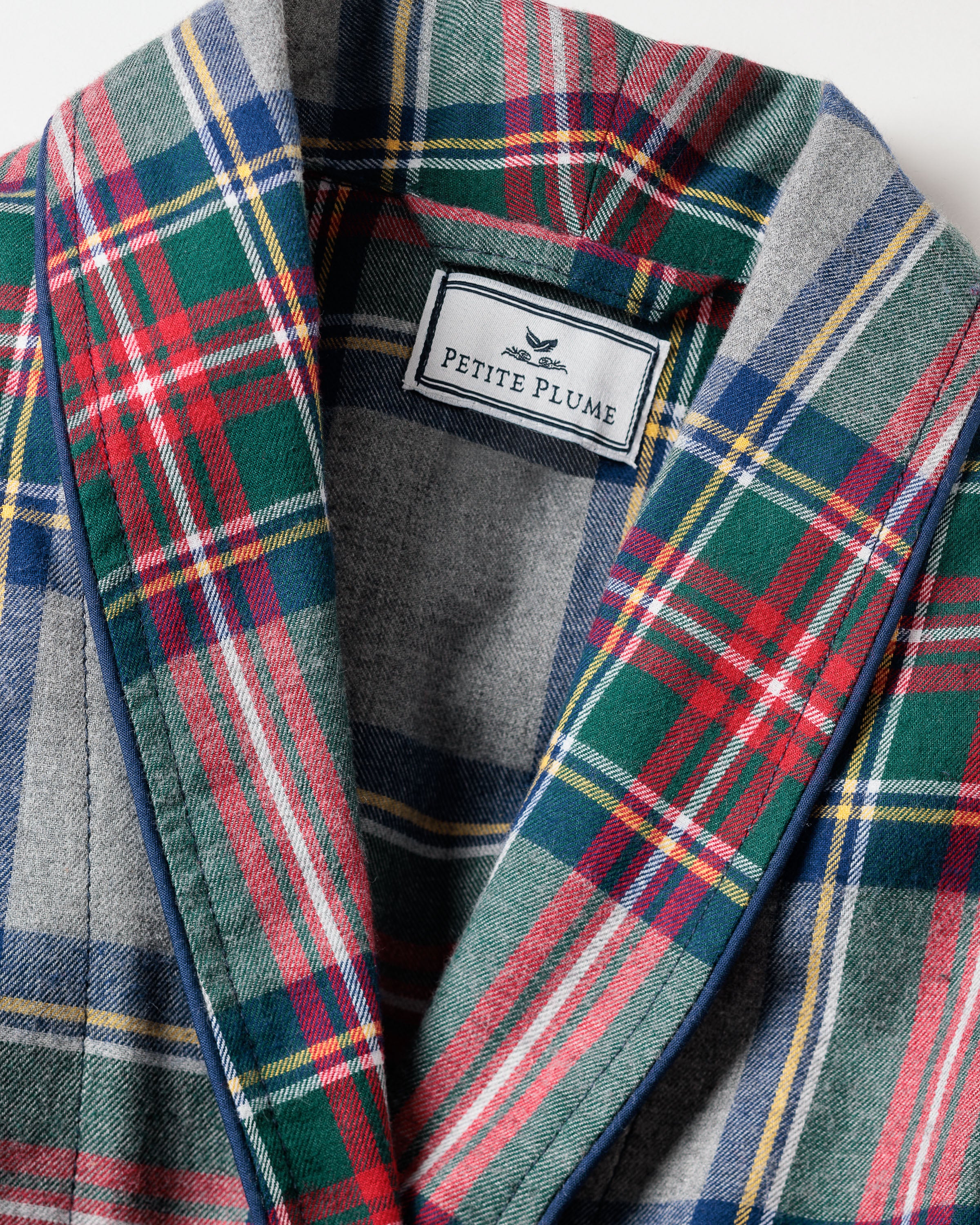 Close-up of the Mens Brushed Cotton Robe in Westminster Tartan by Petite Plume, featuring red, green, blue, and yellow lines on a grey base. The label inside reads PETITE PLUME, with a bird logo, symbolizing luxury sleepwear.