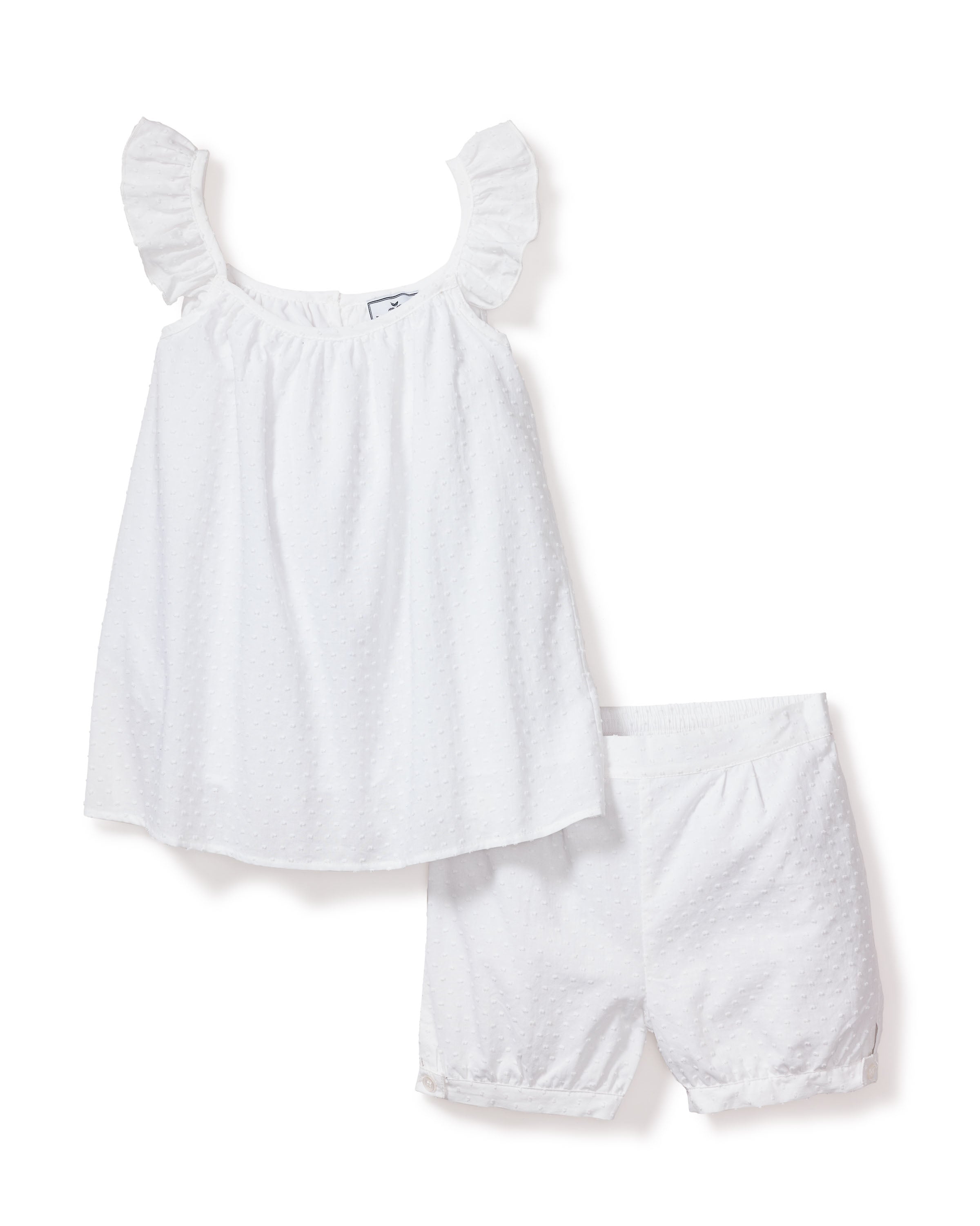 The Girls Swiss Dots Short Set in White by Petite Plume, featuring a sleeveless top with ruffled straps and matching shorts made from textured cotton swiss dot fabric, is displayed on a white background.