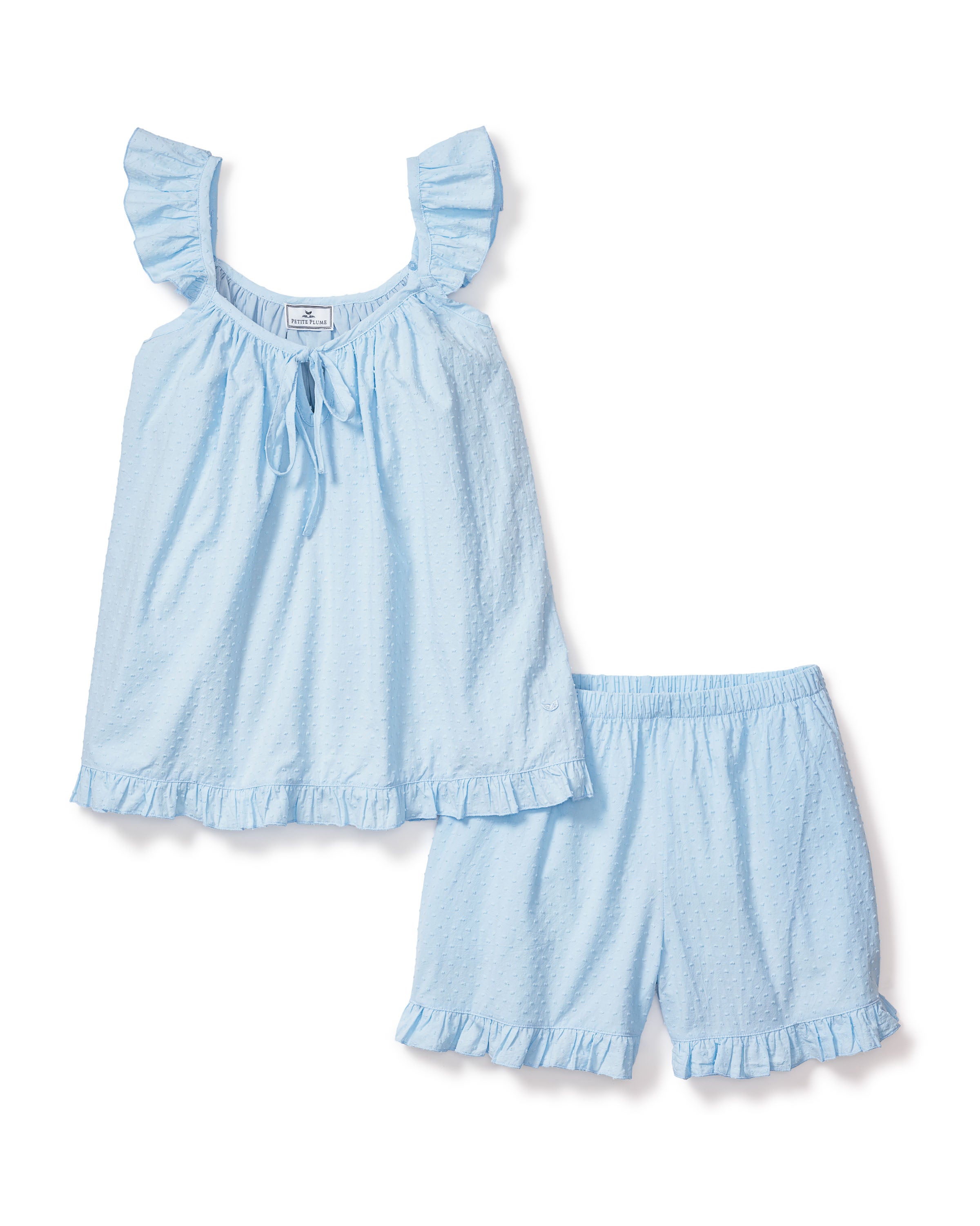 The Womens Swiss Dots Celeste Short Set in Blue by Petite Plume features a sleeveless top with ruffled straps and hem, paired with matching shorts with an elastic waistband and ruffled leg openings. The light blue cotton swiss dot fabric adds texture for a touch of elegance.