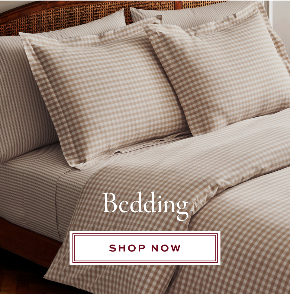 A neatly made bed with beige and white gingham-patterned pillowcases and duvet, and striped sheets. The text reads Bedding and Shop Now in a white box.