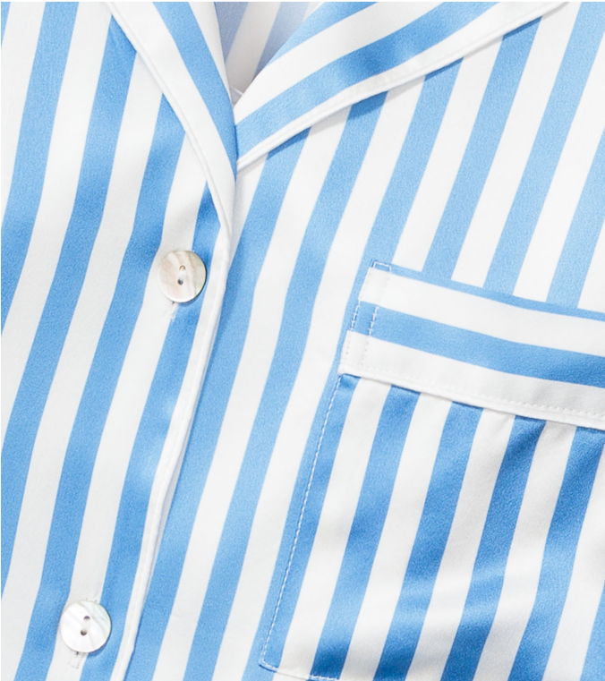 Close-up of a blue and white vertically striped pajama top, featuring white buttons and a pocket on the left side.