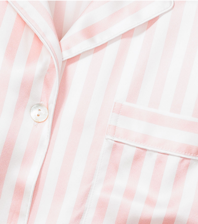 Close-up of a pink and white vertically striped pajama top, showing a button, part of the collar, and a chest pocket.