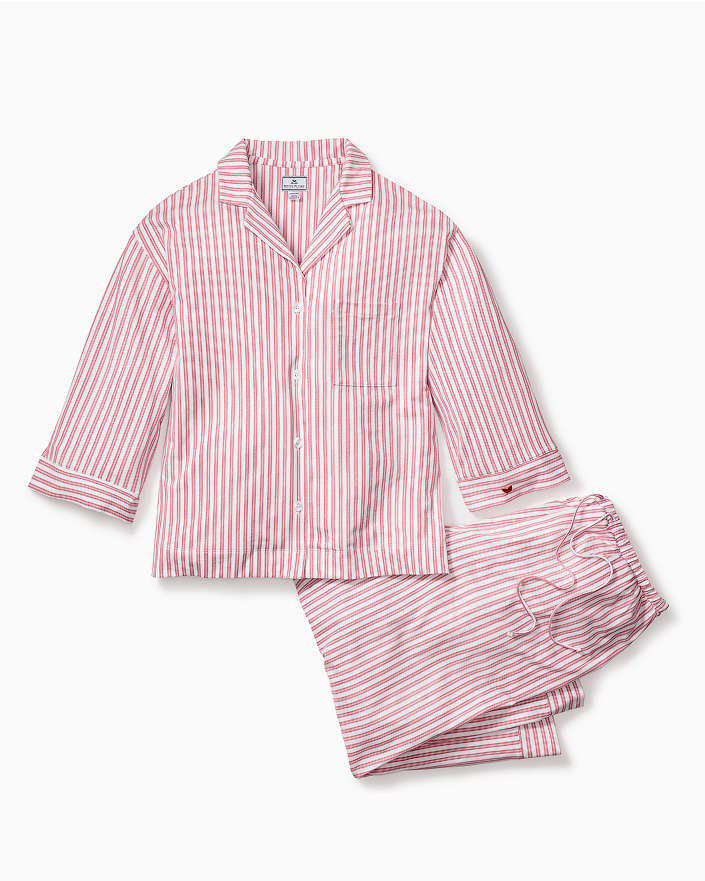 A set of pink and white vertically striped pajamas, featuring a long-sleeve button-up shirt with a collar and matching drawstring pants, laid flat on a white background.