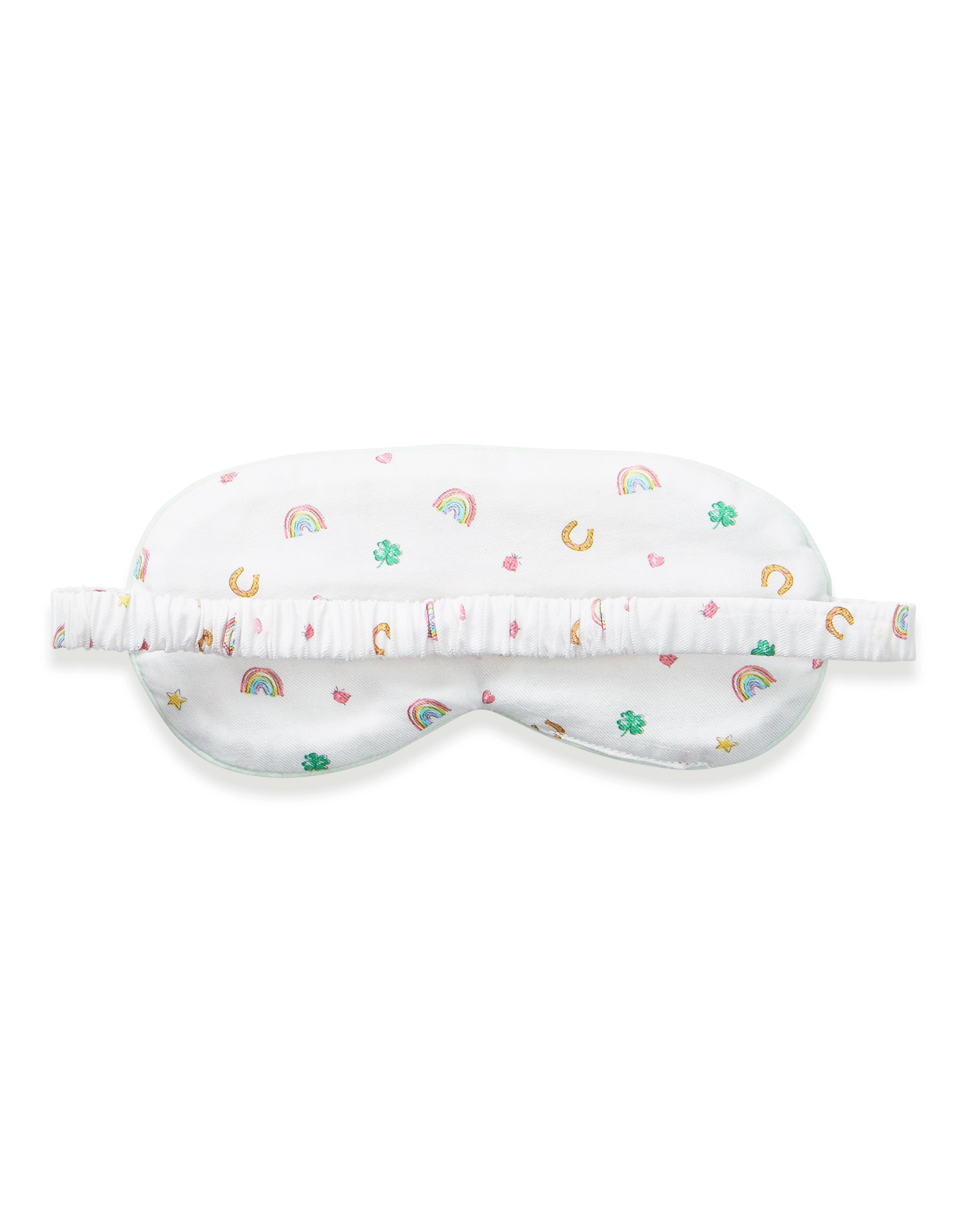 A woman with wavy blonde hair wears the Adult's Twill Sleep Mask in Good Luck Charms and matching patterned pajamas, gazing to the side against a plain neutral background.