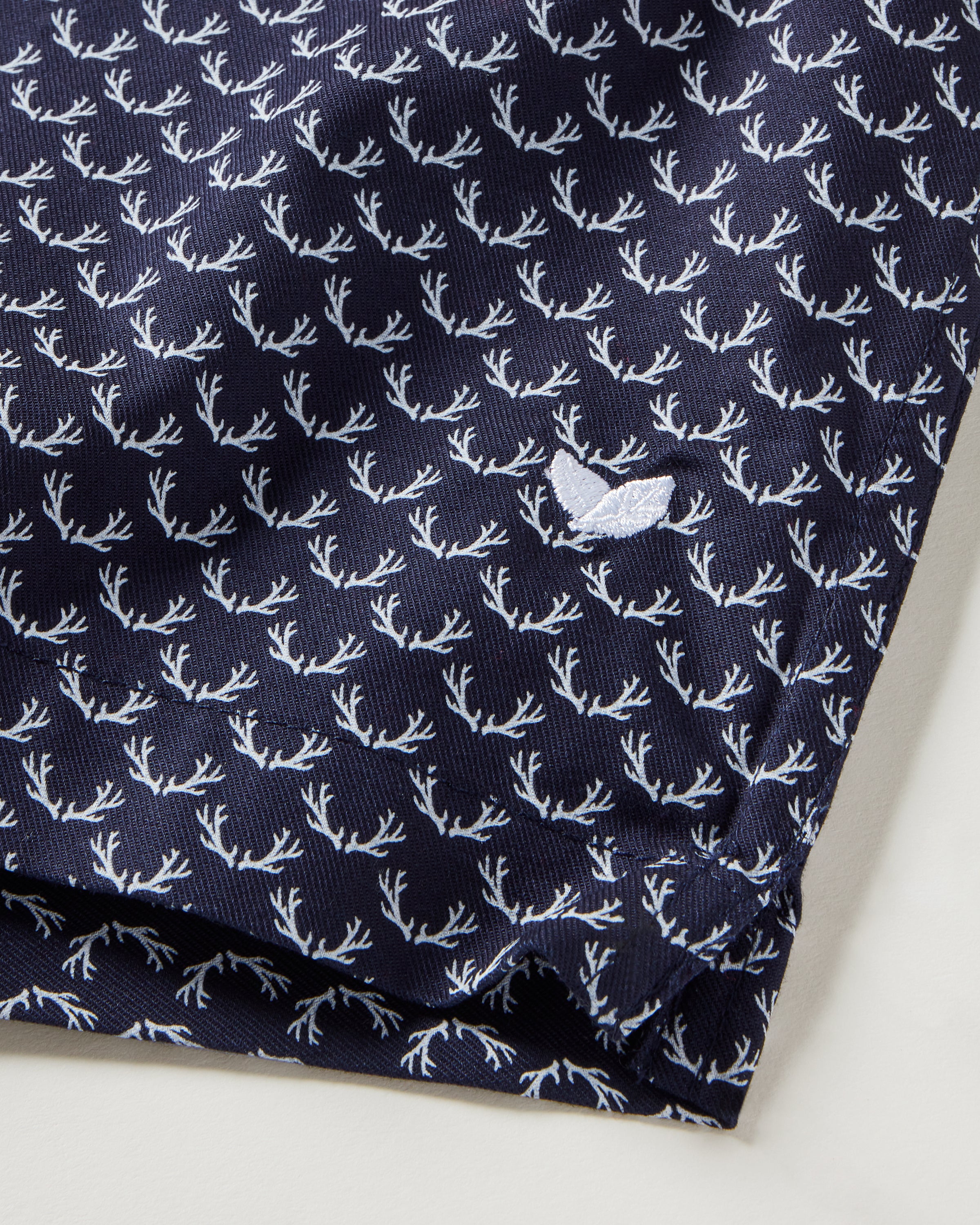 Close-up of Petite Plume Mens Twill 3 Pack Boxers in Windsor Tartan, featuring navy blue woven cotton twill with a small white antler pattern and embroidered bird logo, shown folded at the bottom right corner.