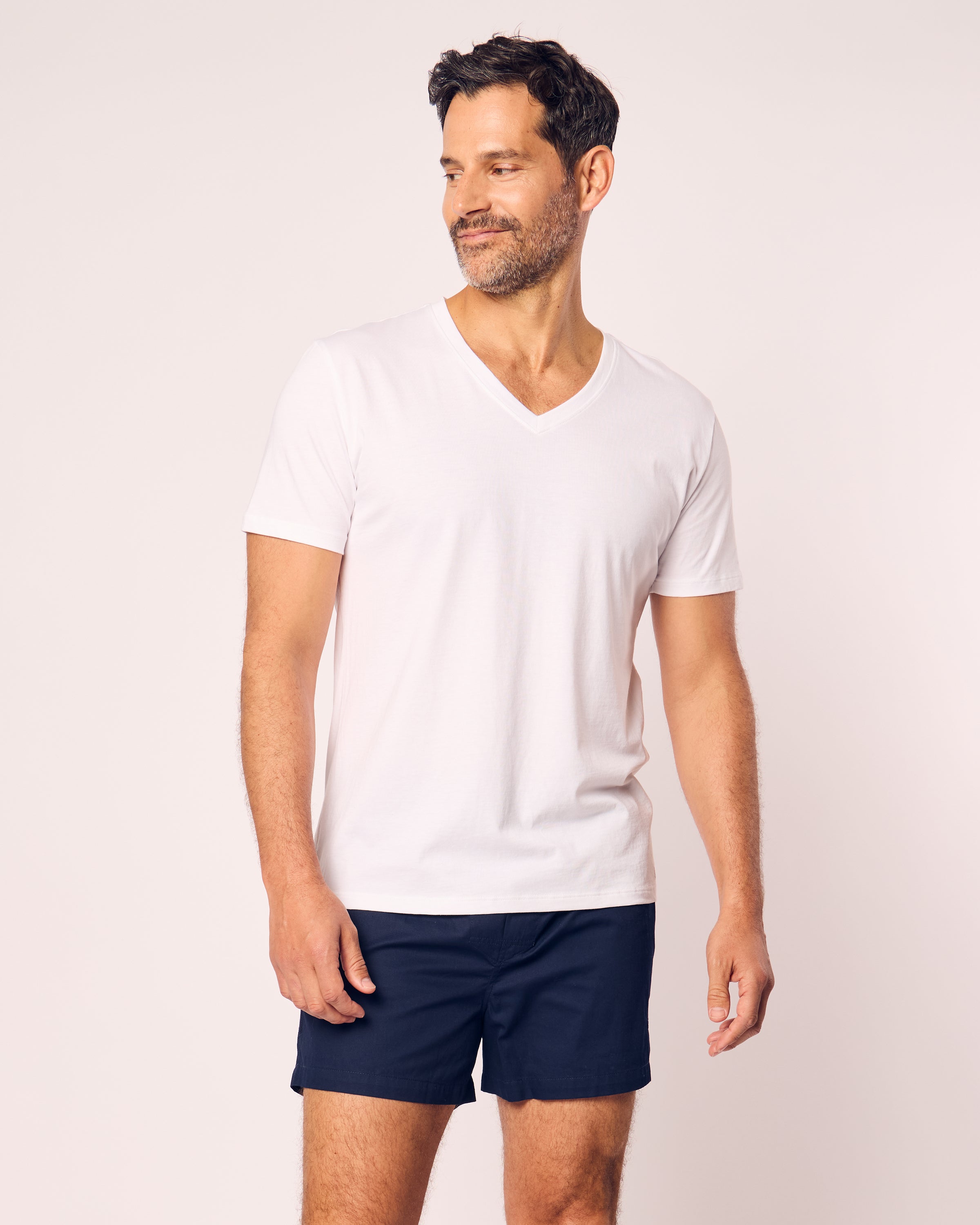 A man with short dark hair and a beard wears Petite Plumes classic-fit plain white V-neck T-shirt and navy Mens Twill boxers. The cotton twill ensures comfort as he gazes left against a neutral backdrop.