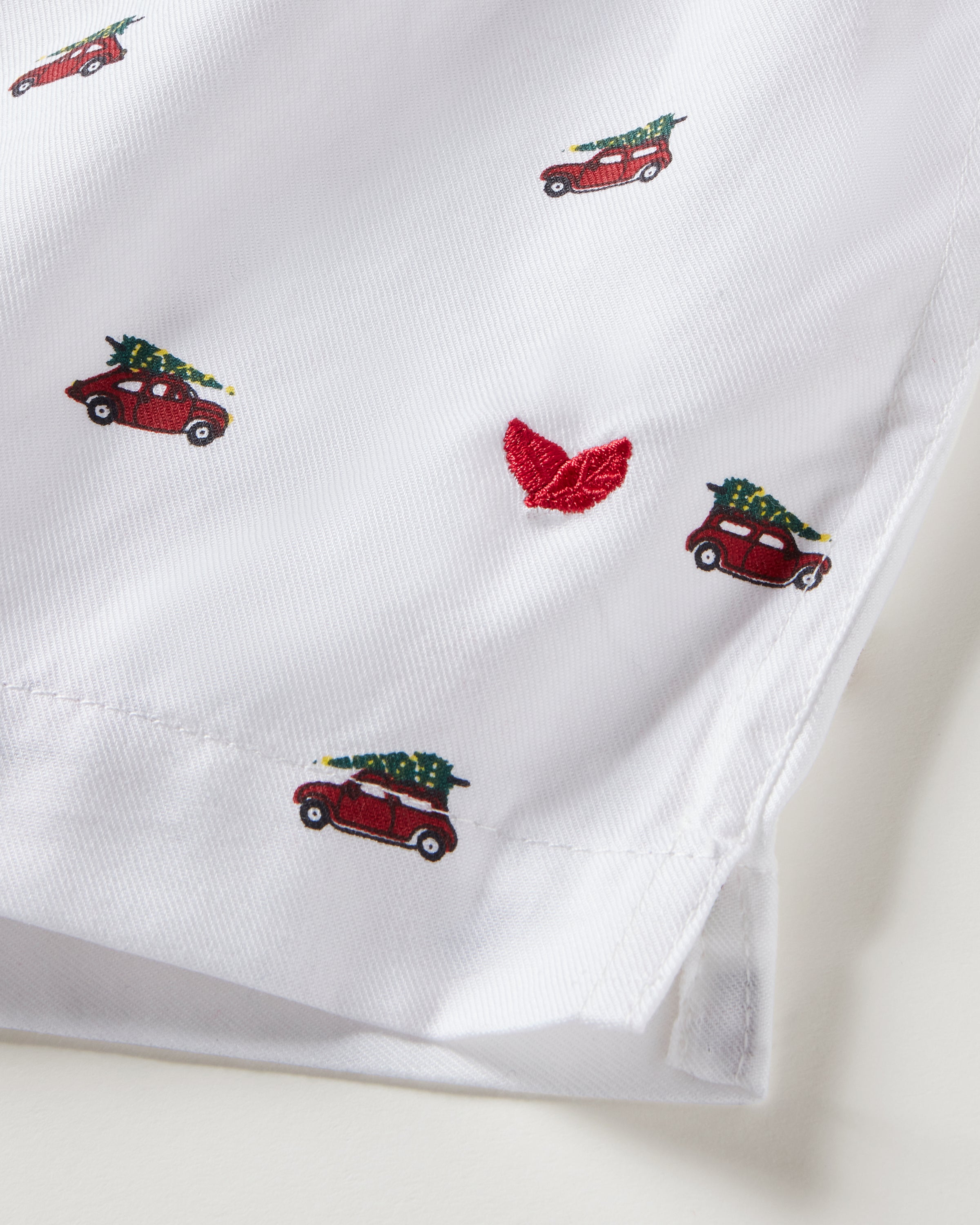 Petite Plumes Mens Twill 3 Pack Boxers in Holiday Red features a woven cotton twill fabric with small red cars carrying Christmas trees. A red embroidered logo near the hem adds charm, making it a festive choice for a classic fit garment.