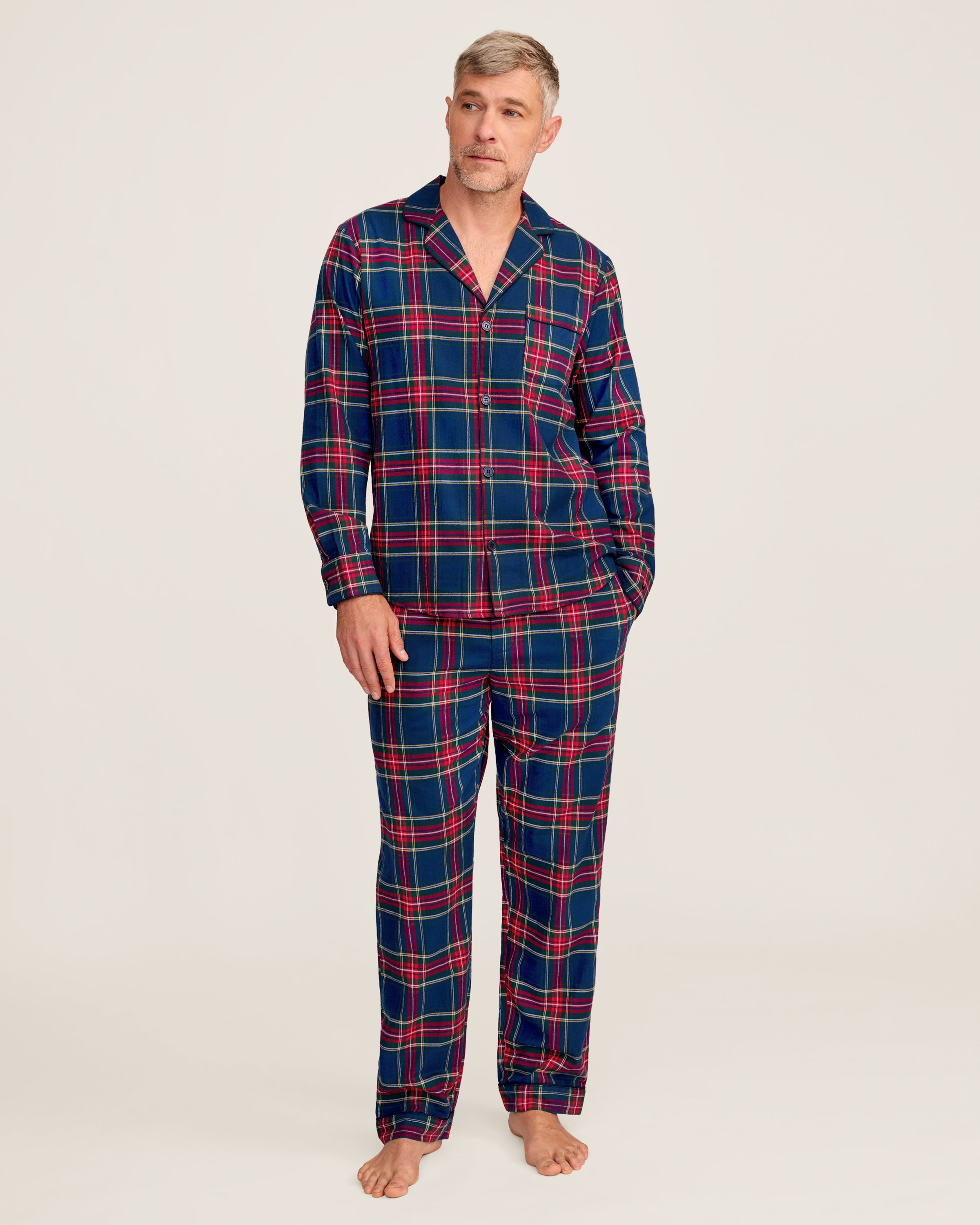 Close-up of a lightweight flannel plaid fabric with red, green, blue, and yellow stripes. The pattern is from Petite Plumes Mens Brushed Cotton Pajama Set in Windsor Tartan, featuring a notched lapel and a single black button.