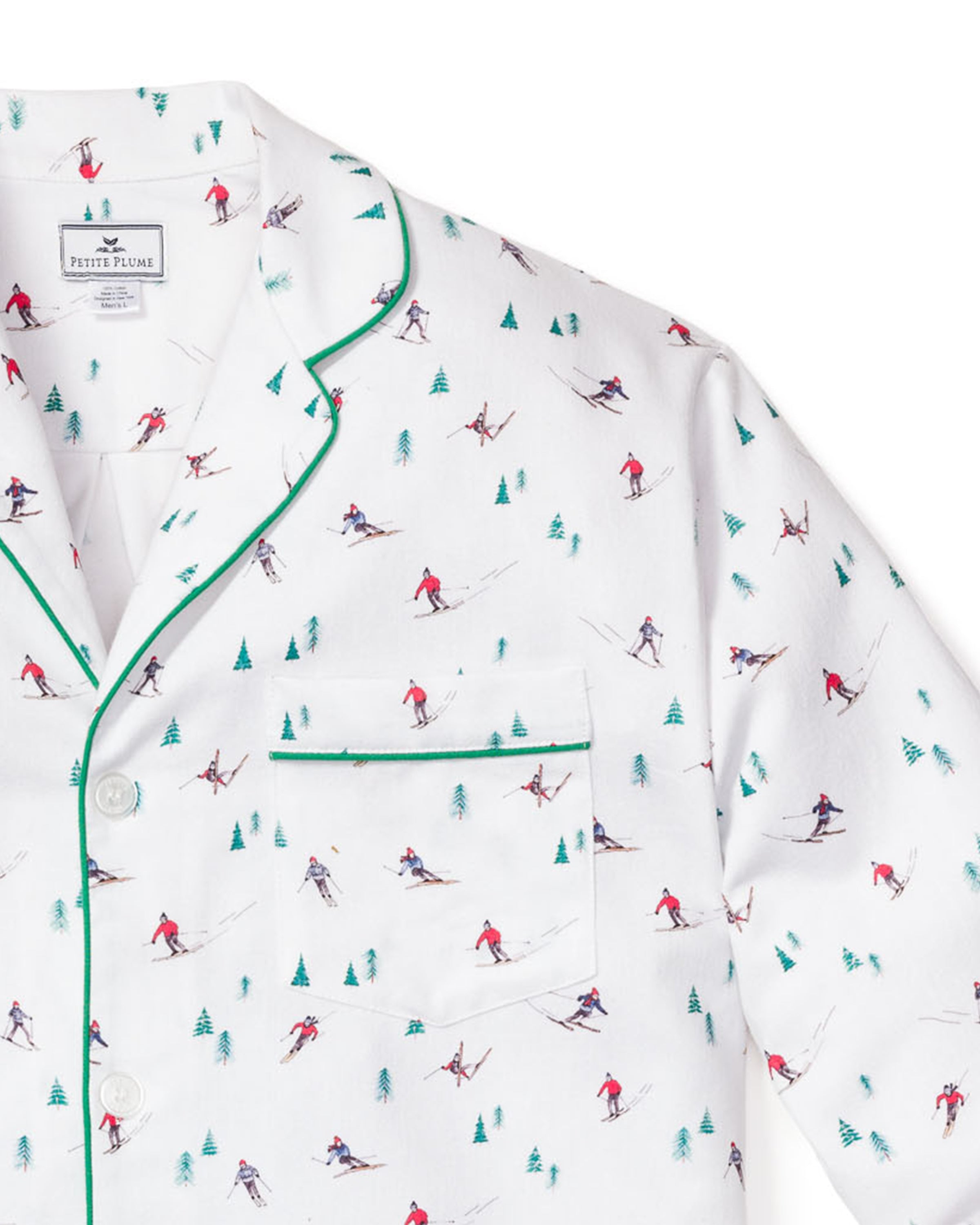 The Mens Flannel Pajama Set in Après Ski by Petite Plume, crafted from 100% cotton, features small skiers in red and blue amidst tiny green trees. It includes a white top with a front pocket, green piping, and white buttons.