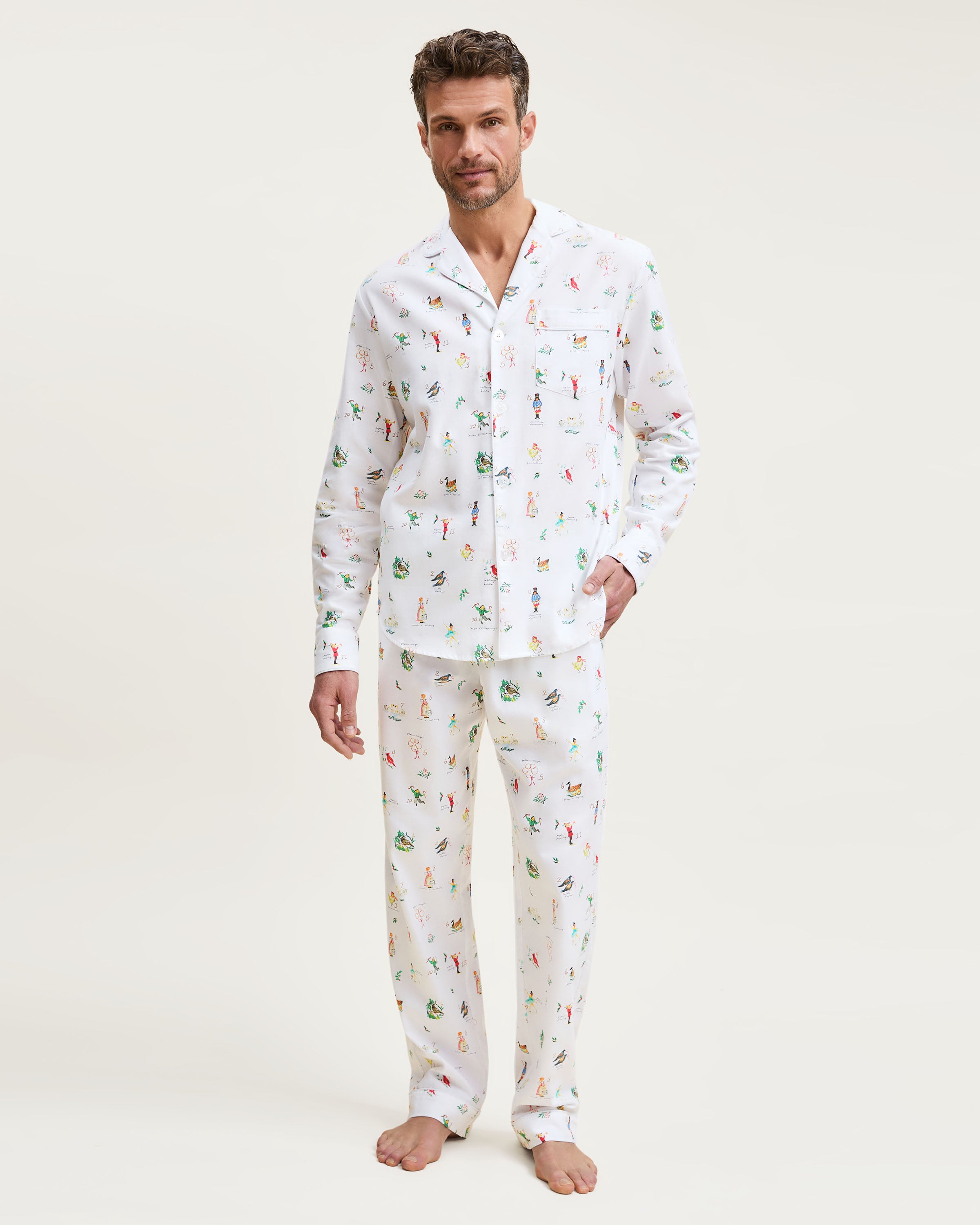 Men's Twill Pajama Set in 12 Days of Christmas: white button-up top and matching pants with a festive print featuring playful animals, palm trees, and people in various poses scattered across the fabric.