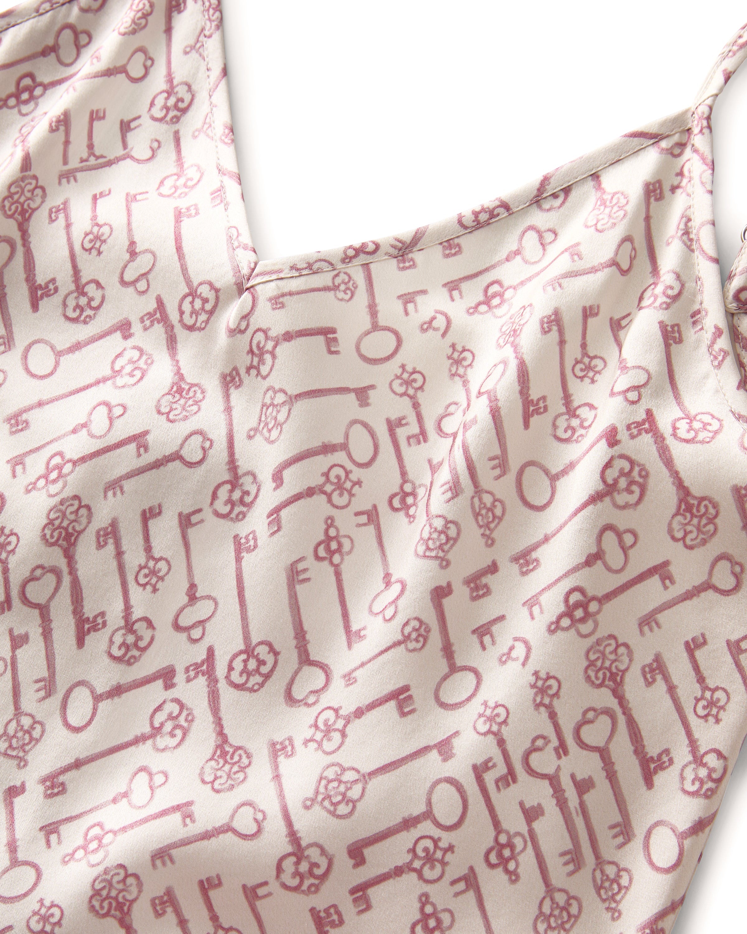 The Women's Silk Cami Short Set in Key to My Heart features a white camisole with thin straps, a crossover front, and matching shorts with an elastic waist, all adorned with a pink vintage-style key pattern.