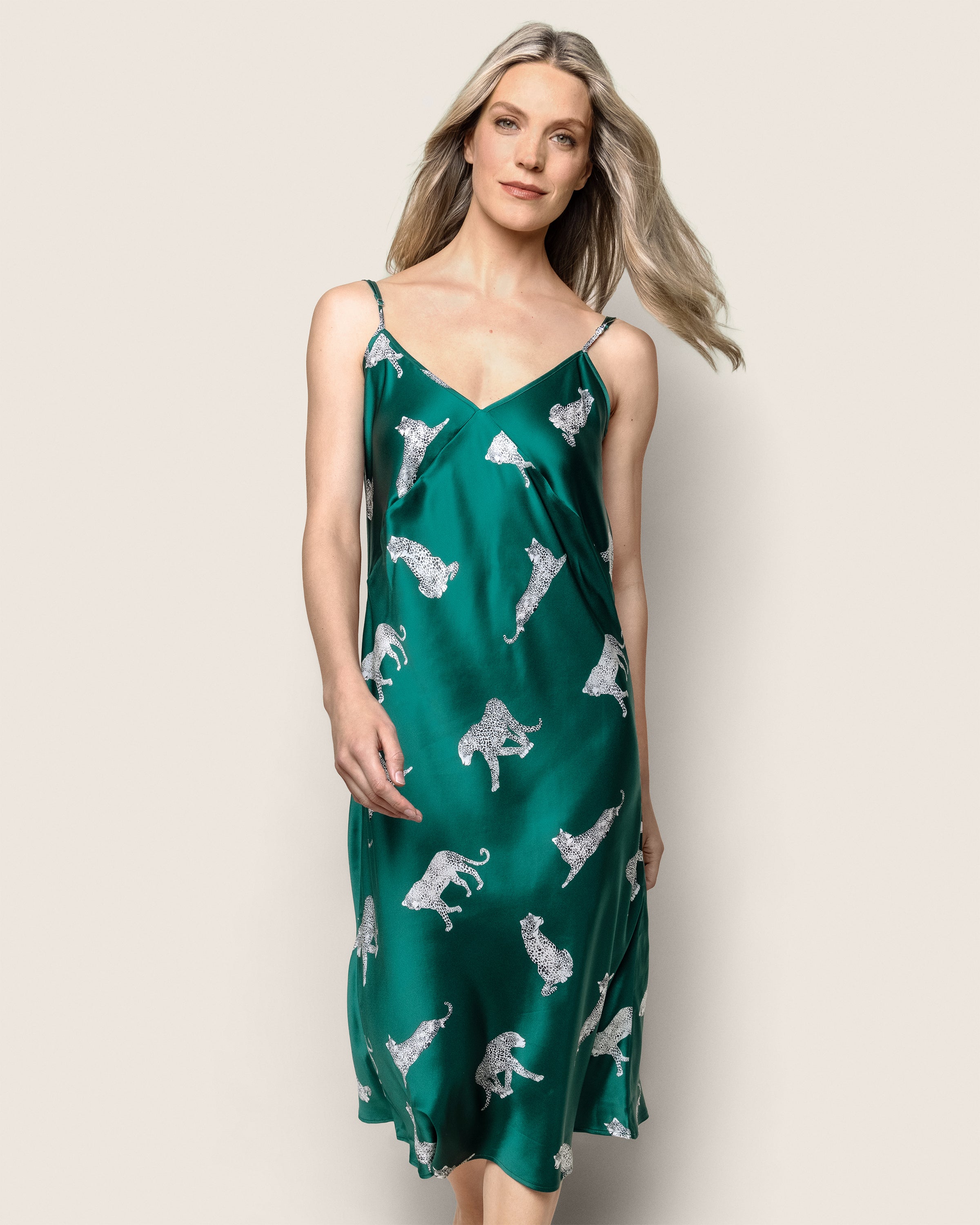 A person in a knee-length, sleeveless Womens Silk Cosette Nightgown by Petite Plume, featuring the Panthère de Luxe leopard print, strolls against a plain background. The dress effortlessly complements their long blonde hair.