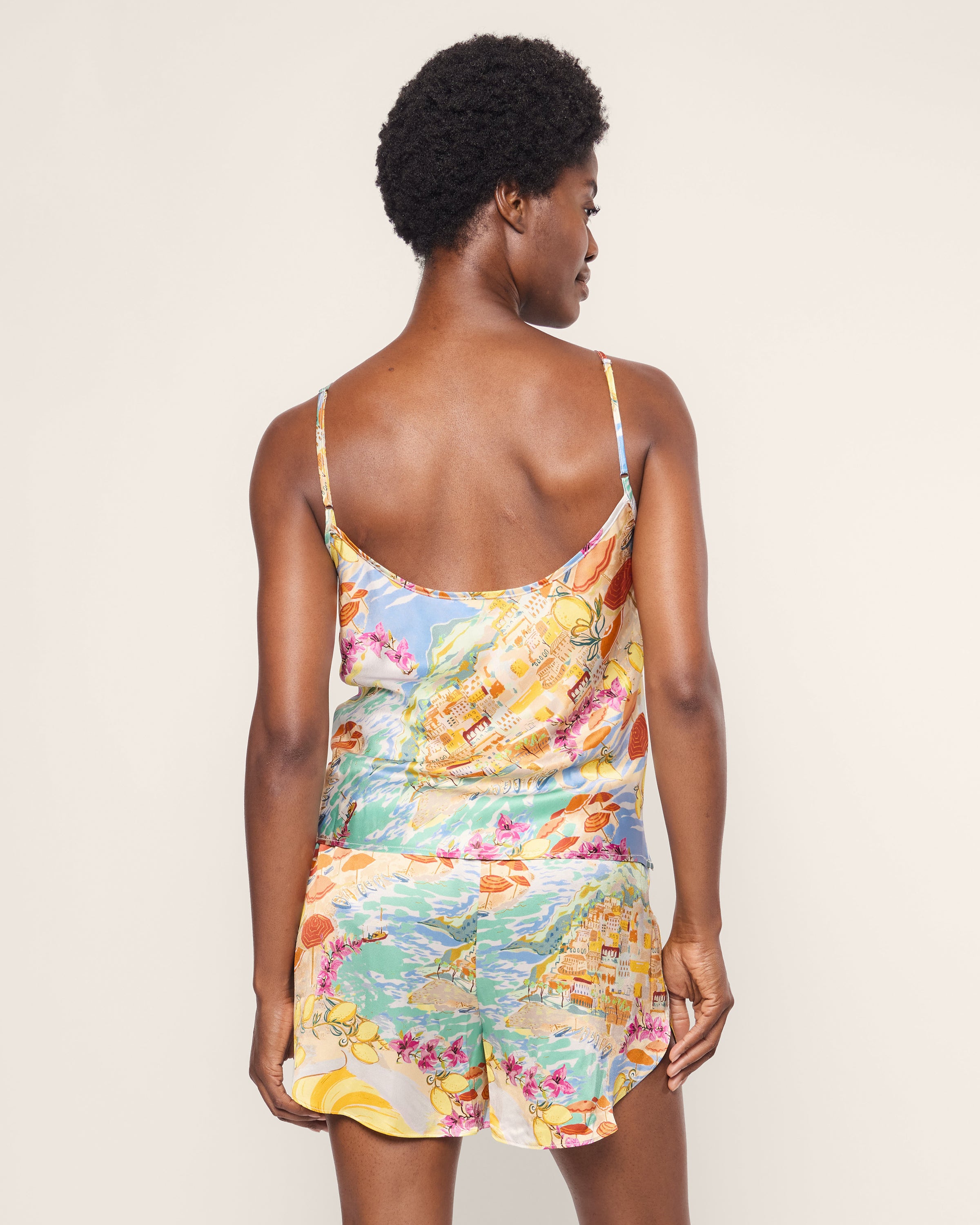 A person with short curly hair wears Petite Plumes Womens Silk Cami Short Set in La Dolce Vita. They stand against a plain background, embodying luxury sleepwear sophistication.