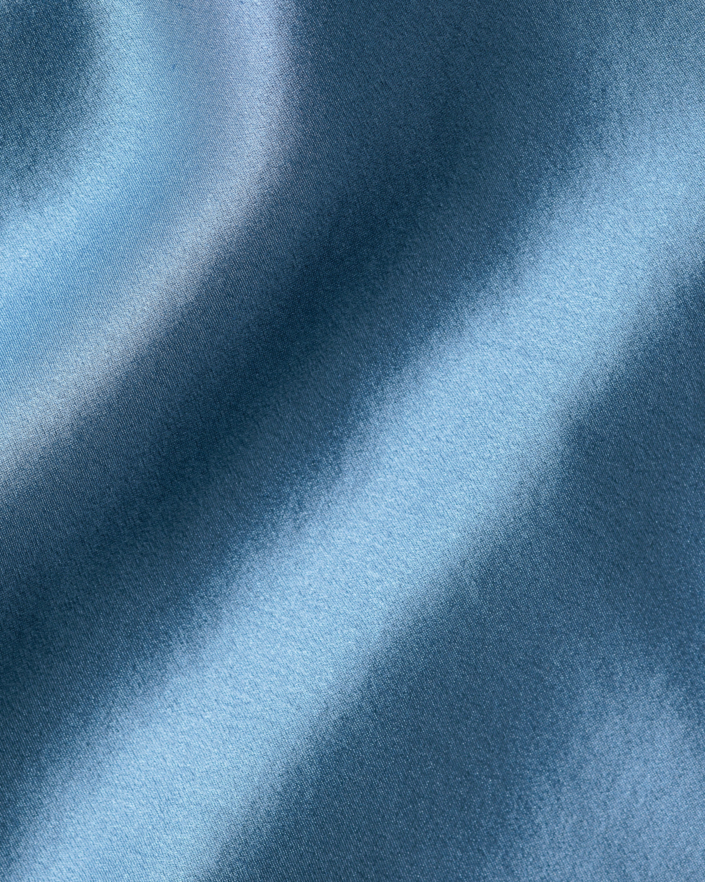 A close-up of Petite Plumes Womens Silk Lace Cami Short Set in Mystique Blue shows a smooth mulberry silk fabric with a gradient blue pattern, creating a soft and wavy texture.