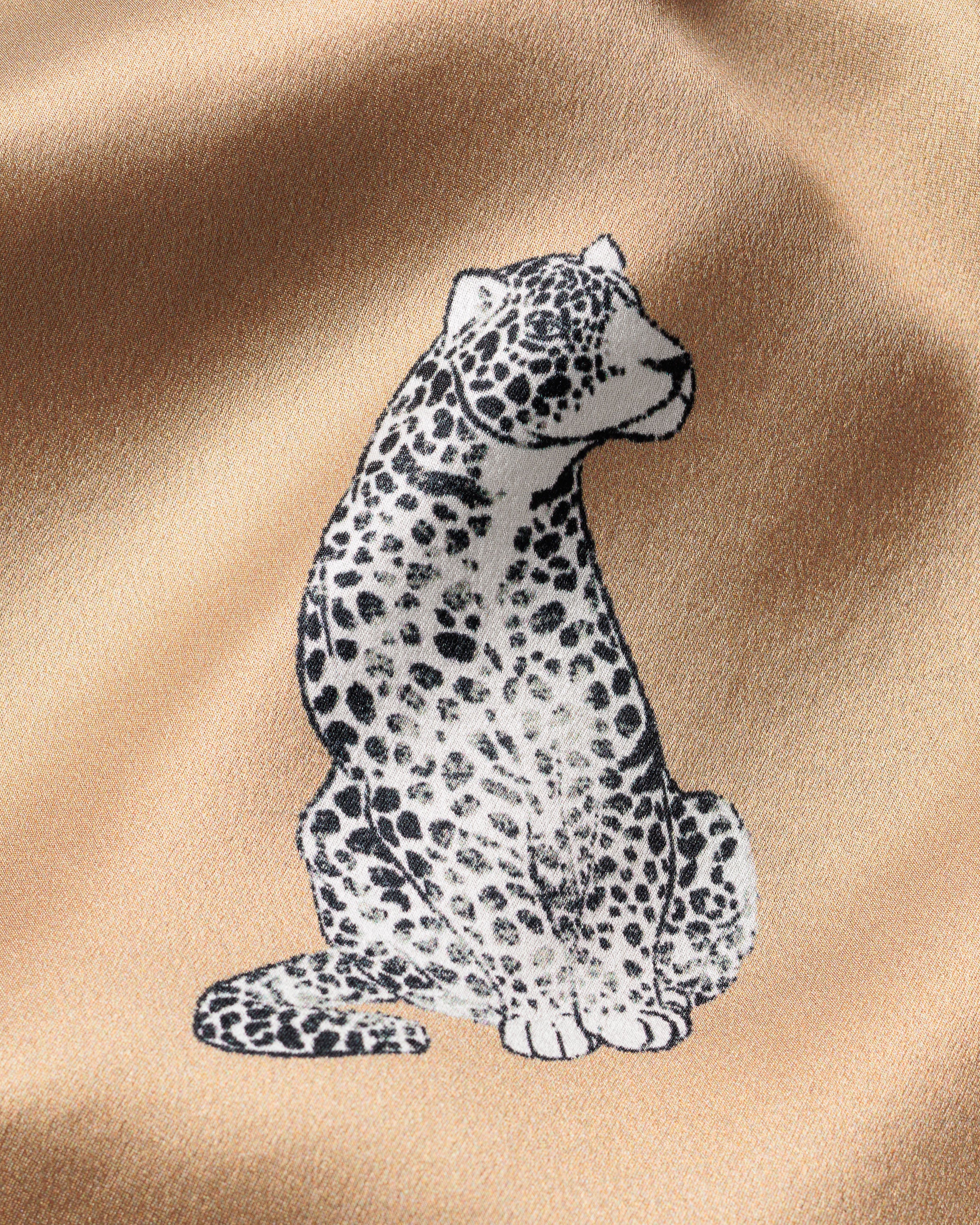 Illustration of a leopard with a stylized black and white dotted pattern on tan mulberry silk, reminiscent of Petite Plumes Womens Silk Nightshirt in Panthère Champagne adorned with an exquisite panther motif.
