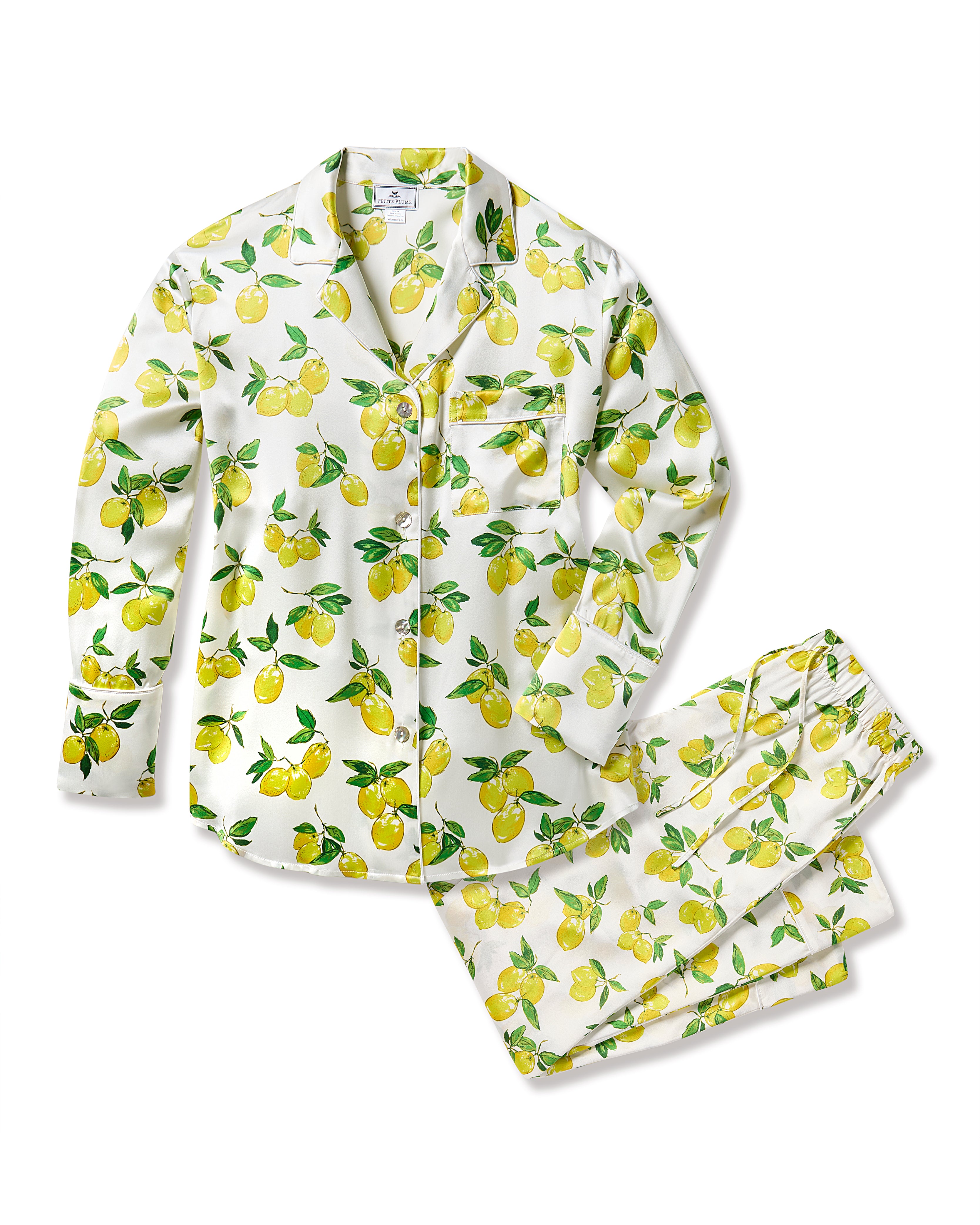 The Womens Silk Pajama Set in Amalfi Lemons by Petite Plume features a button-up shirt and pants with a vibrant lemon print on white. Made from limited-edition, machine-washable silk, it showcases yellow lemons with green leaves for a fresh look.