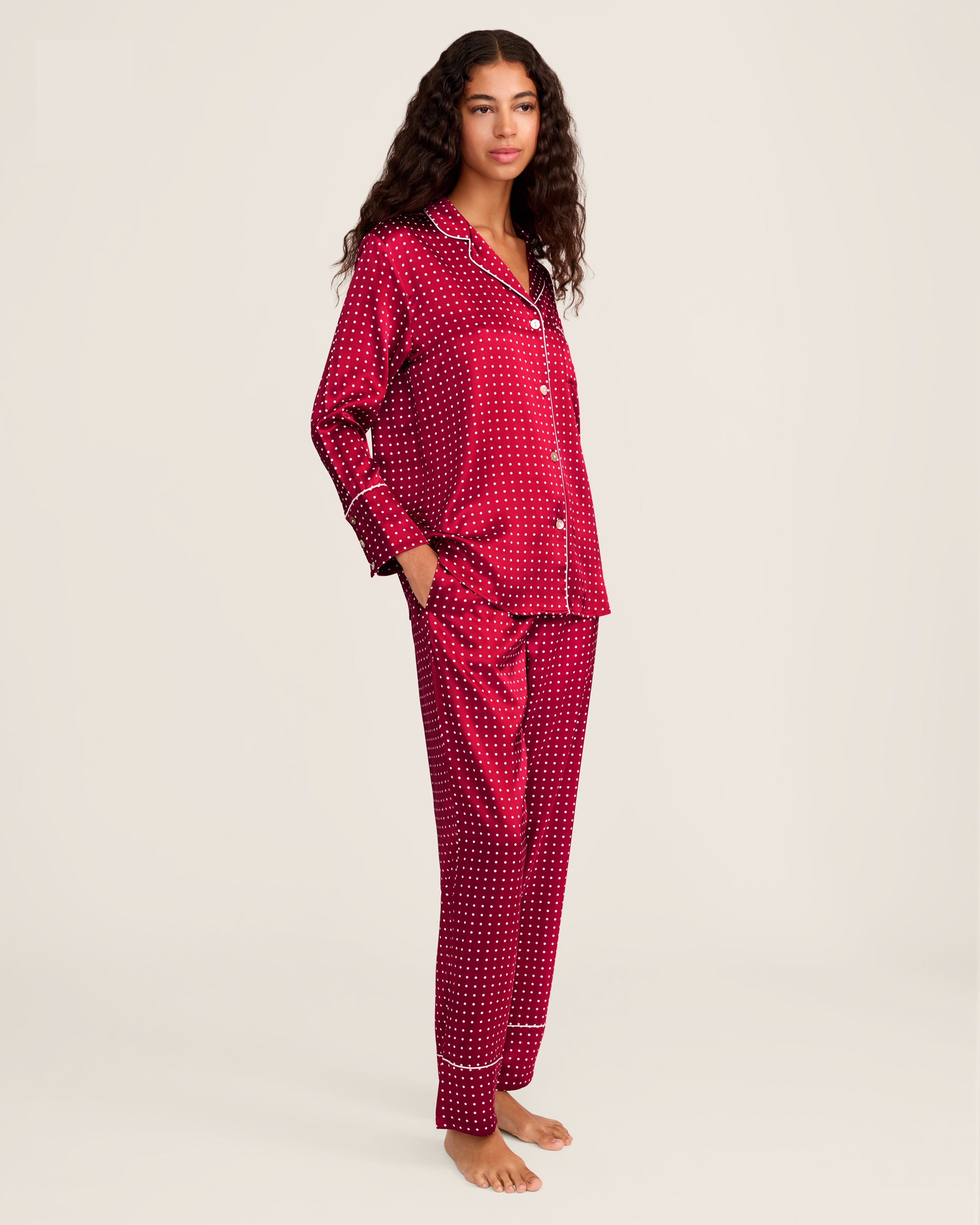 Experience luxury sleepwear with Petite Plumes Womens Silk Pajama Set in Bordeaux Polka Dot, featuring a bright red button-up long-sleeve top with white dots and piping, crafted from breathable mulberry silk, paired with matching pants.