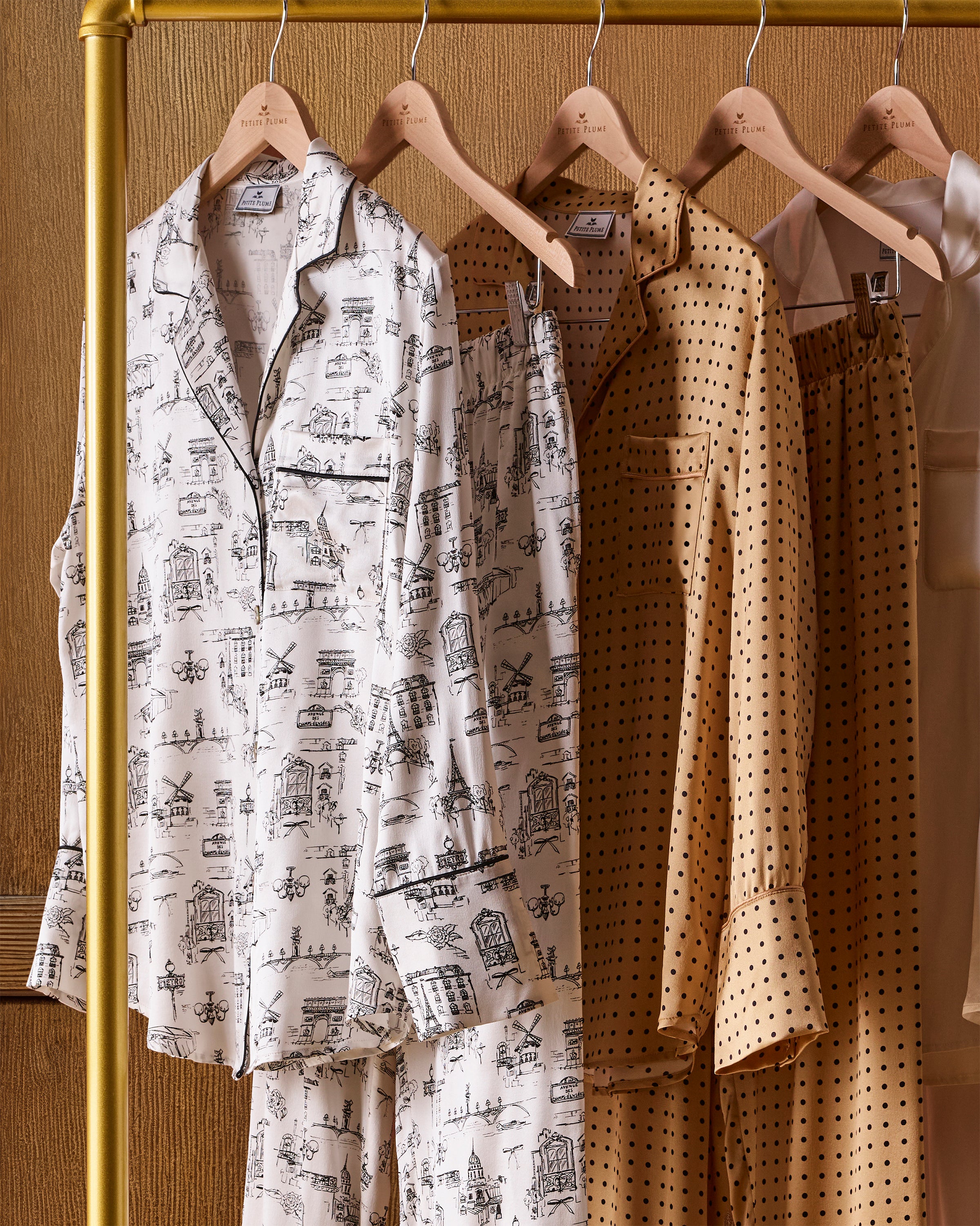 Women's Silk Pajama Set in Parisian Toile: white button-up with black piping, illustrated with buildings and trees. Includes long-sleeve top with chest pocket and matching long pants featuring an elastic waistband.