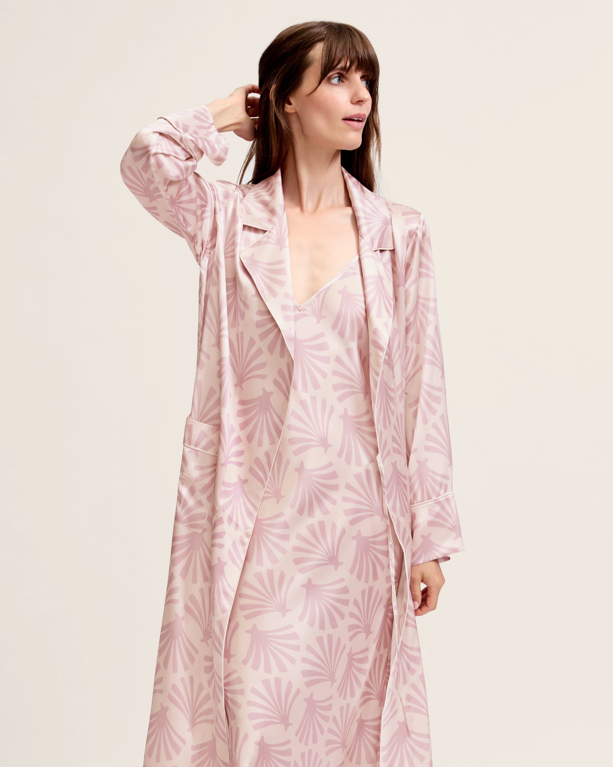 The Women's Silk Robe in Blush Tide features a light pink hue with a darker pink geometric pattern, notched collar, long sleeves, and a matching waist belt.