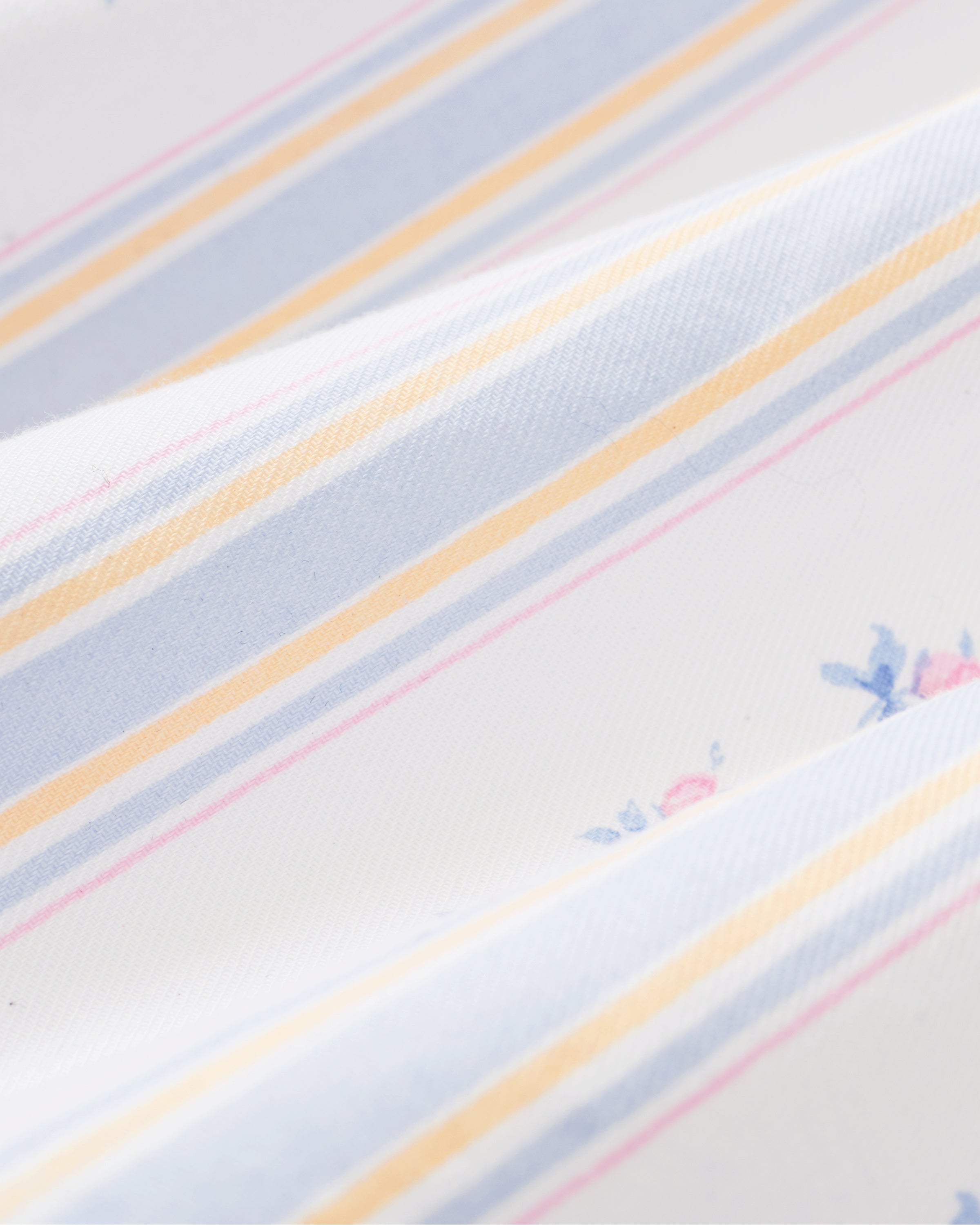 A woman stands barefoot against a plain light background wearing the Women's Twill Clara Nightgown in Cottage Stripe, featuring a long, loose fit with pastel vertical stripes and ruffled shoulder straps.