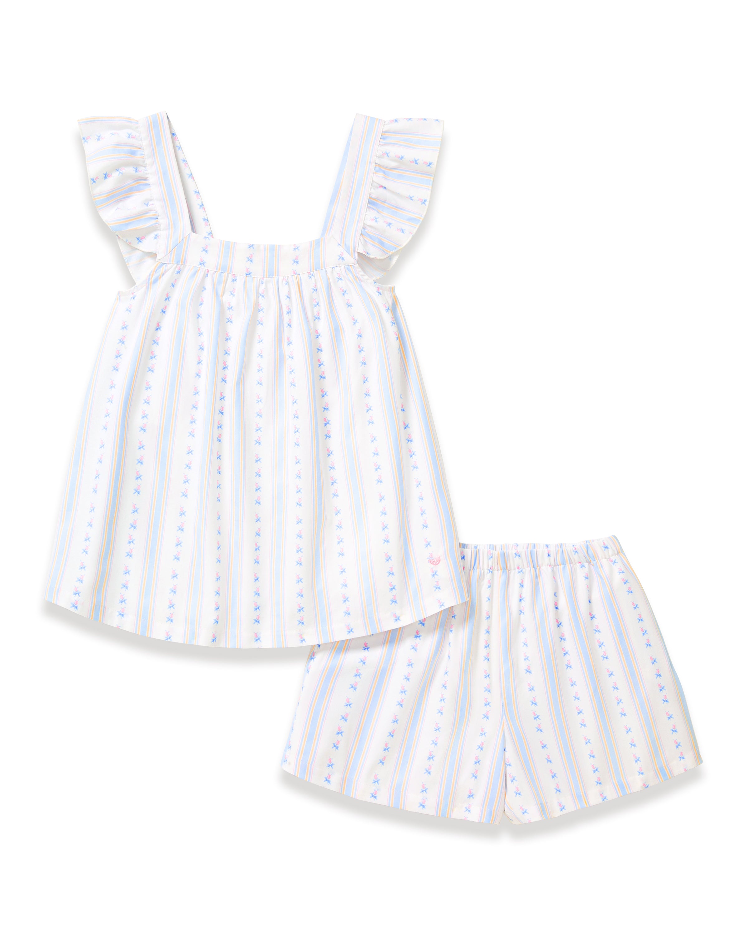 A woman with long curly hair models the Women's Twill Clara Short Set in Cottage Stripe—a loose, sleeveless pajama set with ruffled shoulders and shorts, featuring white fabric with pastel stripes and floral patterns—against a plain background.