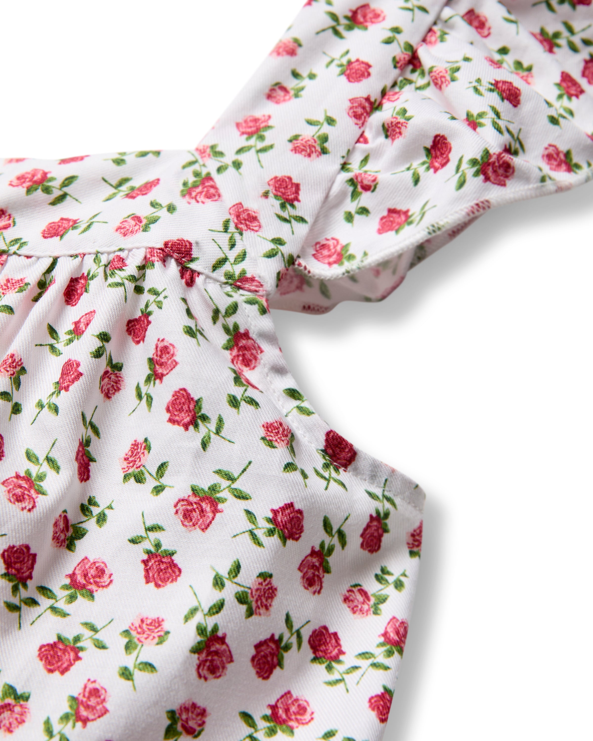 Close-up of a sleeveless white fabric with pink rose motifs, ideal for Petite Plumes Womens Twill Clara Short Set in Petite Petals. Gathered shoulder detail adds charm to this elegant sleepwear piece.