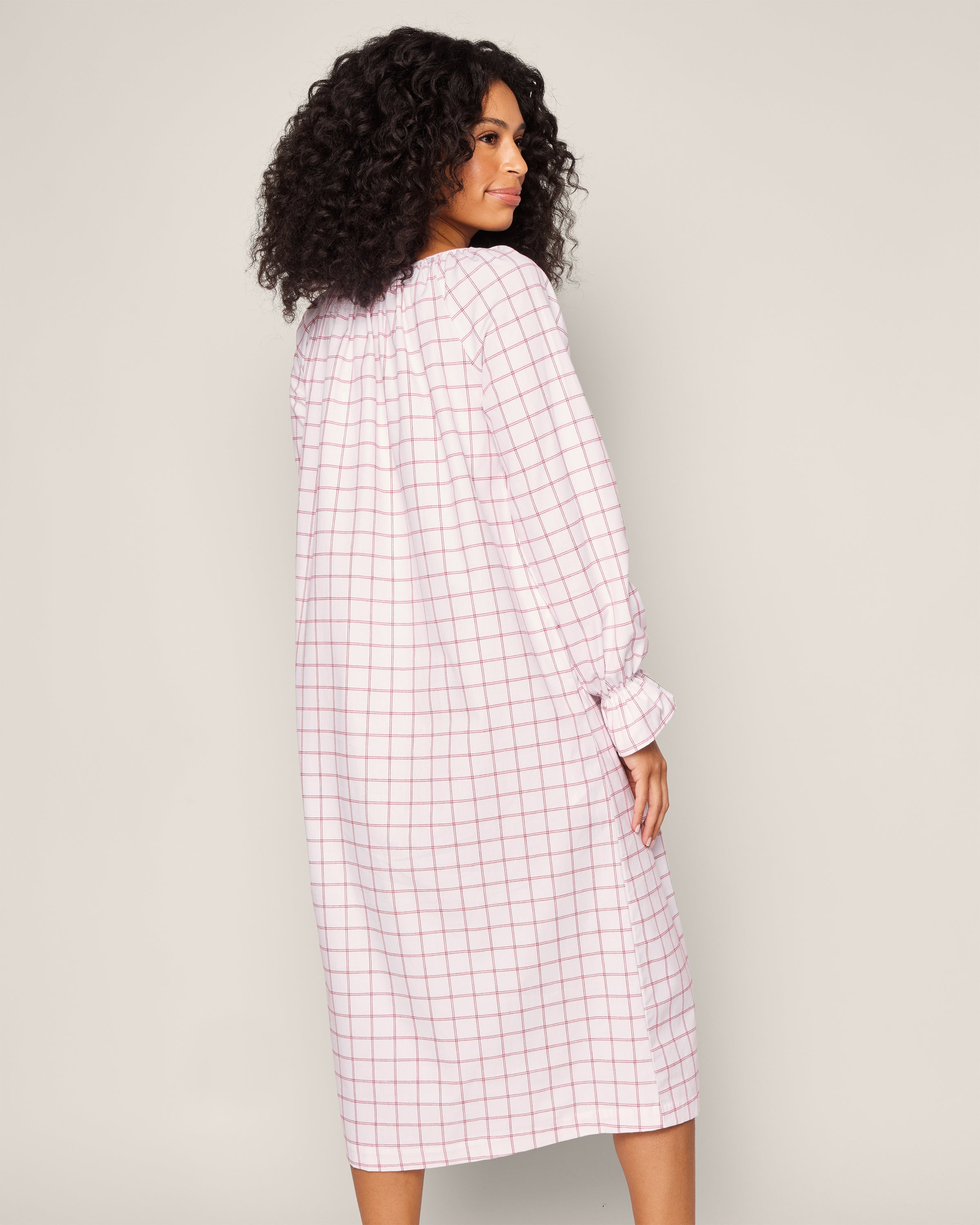 A woman with curly hair wears Petite Plumes Womens Twill Delphine Nightgown in Garnet Tattersall, facing away from the camera.