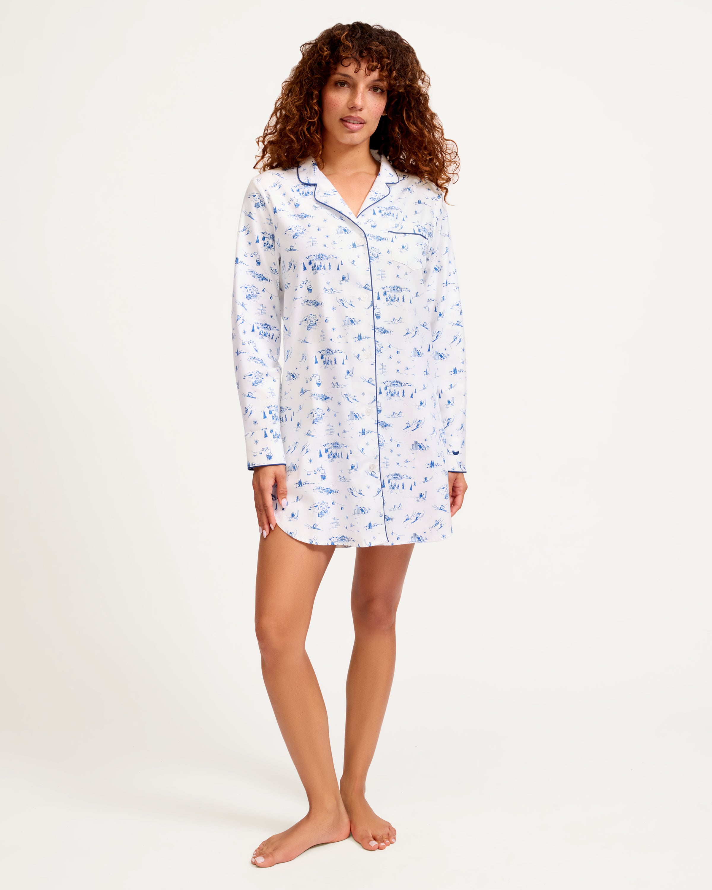 The Women's Twill Nightshirt in Chalet Toile features long sleeves, a white button-up design, a blue scenic print, and dark blue piping on the collar, cuffs, and pocket.
