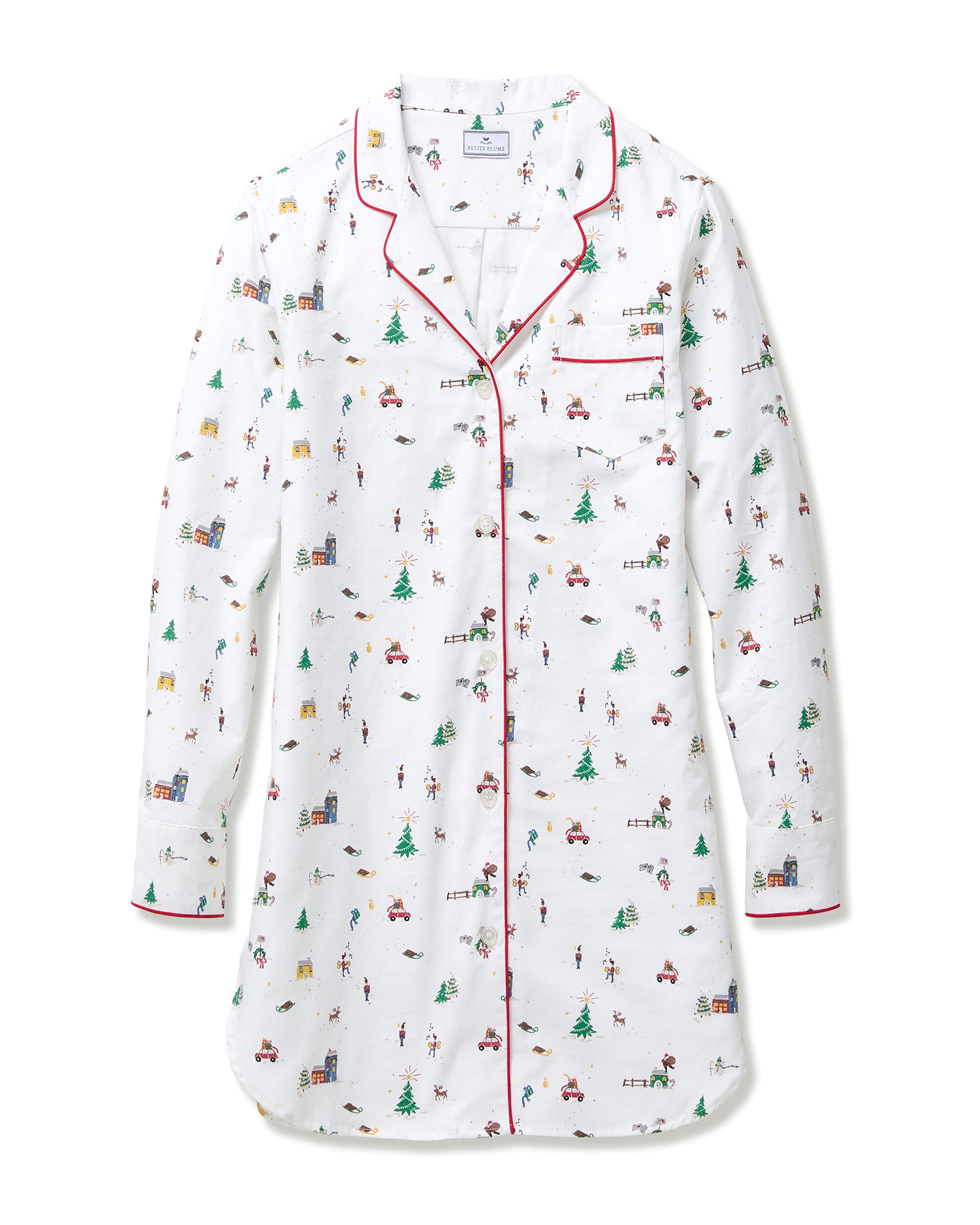 The Women's Twill Nightshirt in Holiday Town features a white, long-sleeve design with festive prints of trees, cars, skiers, and houses, finished with red piping on the collar, cuffs, and pocket trim.