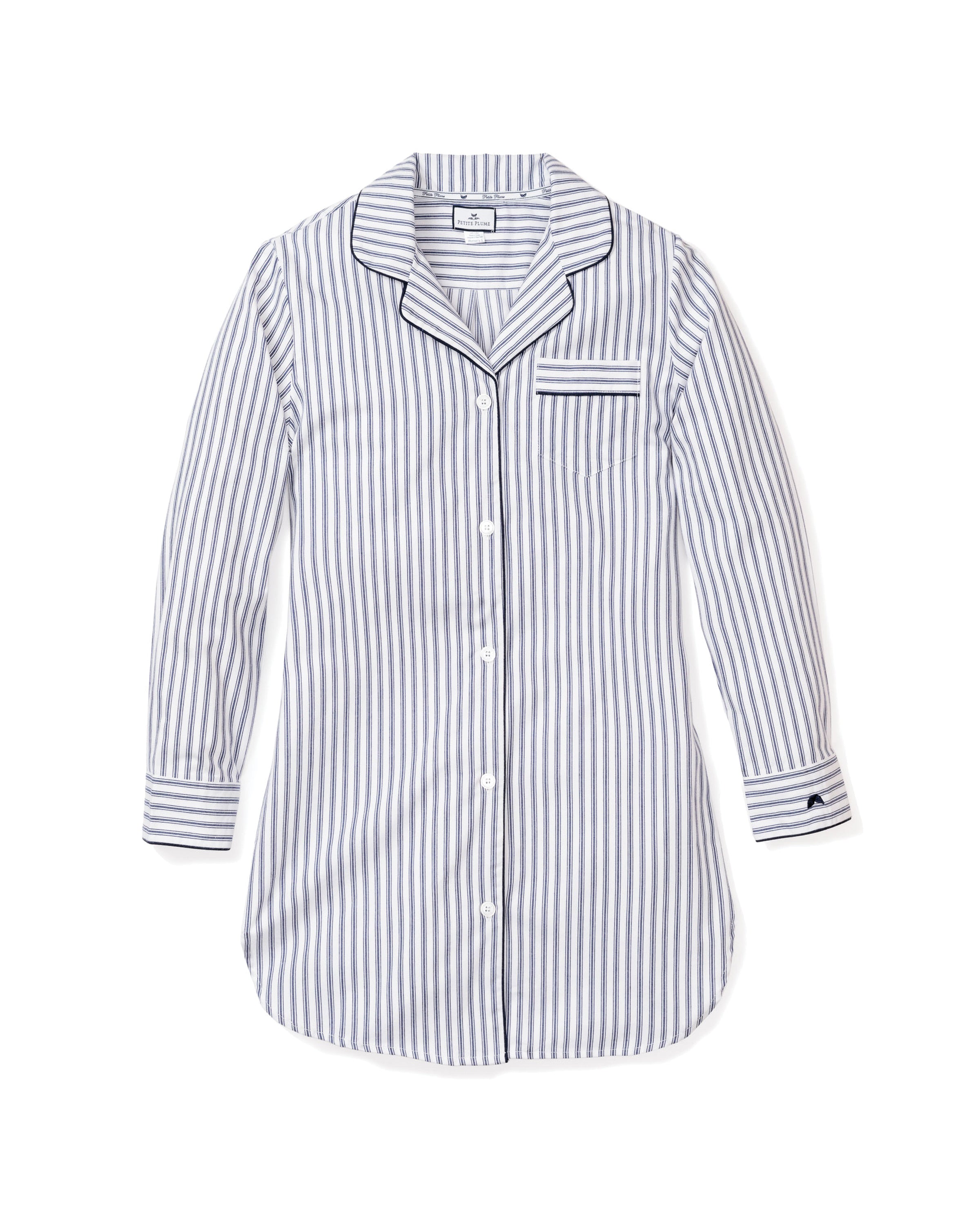 The Womens Twill Nightshirt in Navy French Ticking by Petite Plume is a long-sleeved, button-up nightshirt with a classic pajama design featuring blue and white vertical stripes, soft cotton twill, a chest pocket, and black piped trim on the collar, front, and cuffs.