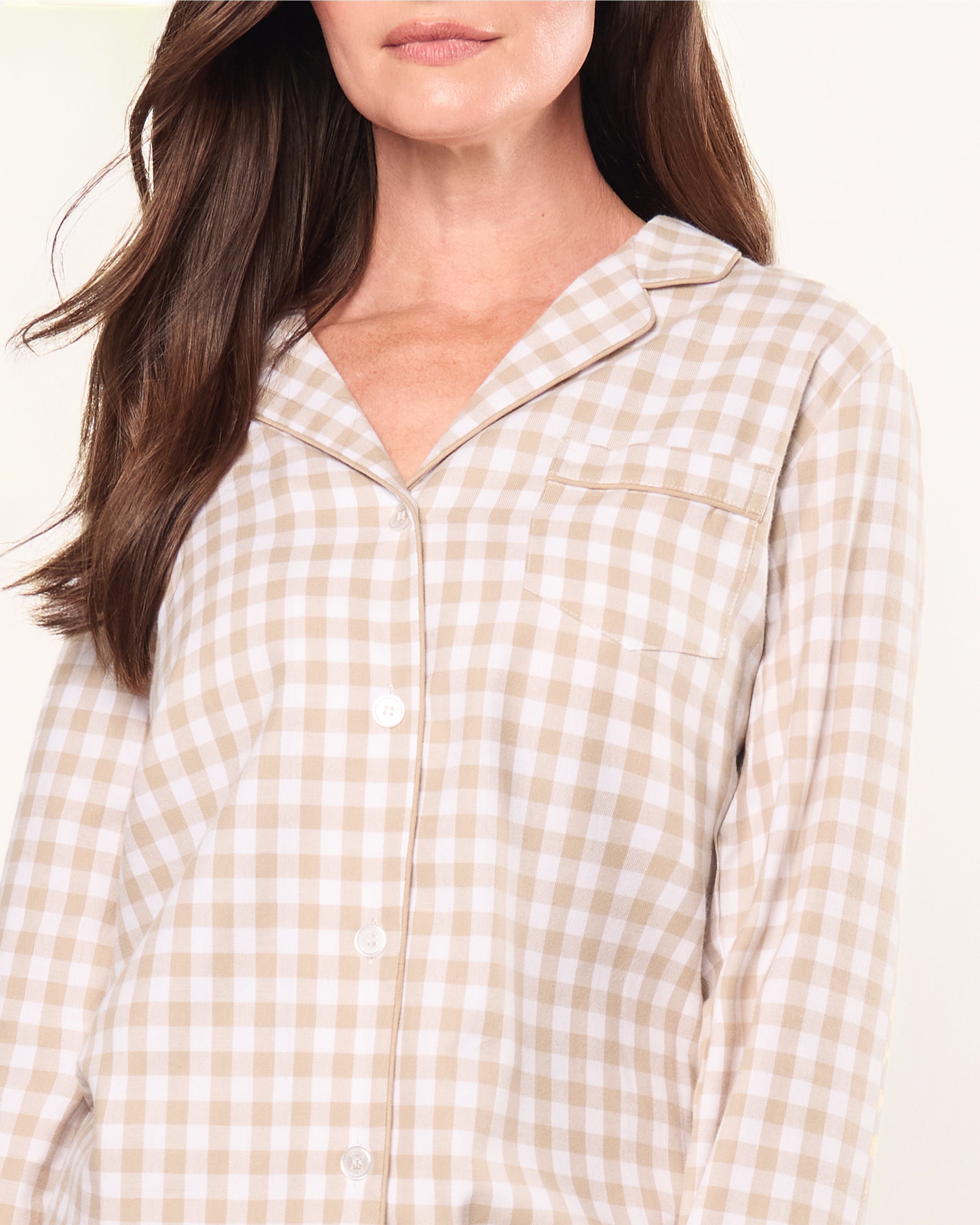 The Women's Twill Pajama Set in Camel Gingham features a beige and white check long-sleeve, button-up top with chest pocket and matching drawstring pants, displayed neatly on a white background.